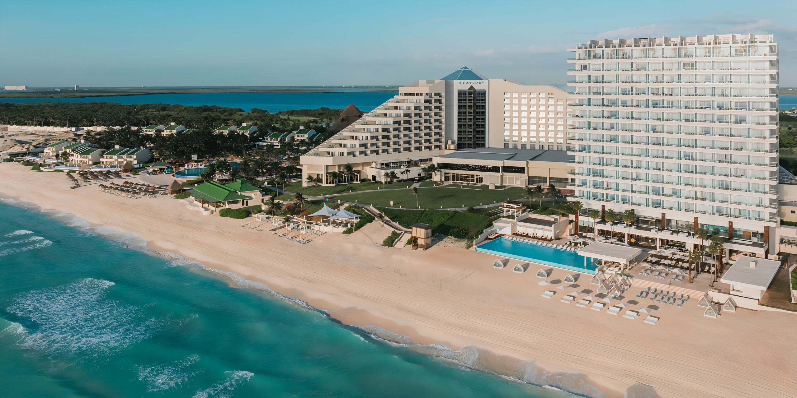 Aerial view of Iberostar Selection Cancun beachfront resort with modern buildings and swimming pools.