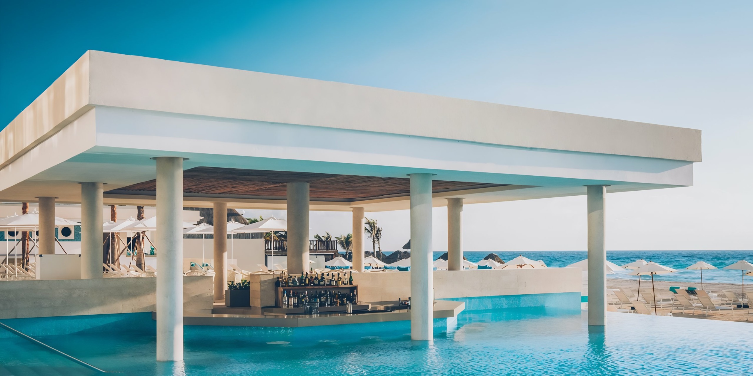Luxurious poolside bar with ocean view under a modern, open-air pavilion at Iberostar Selection Cancun.