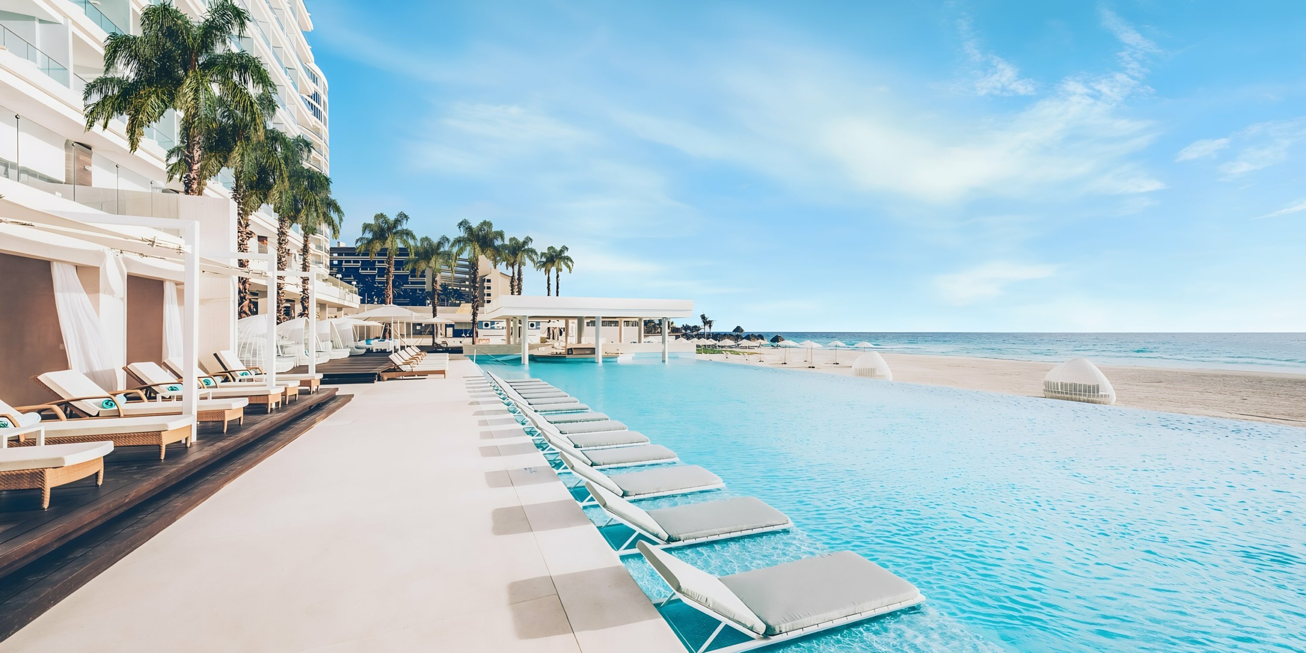 Iberostar Selection Cancun beachfront resort with an infinity pool and sun loungers.