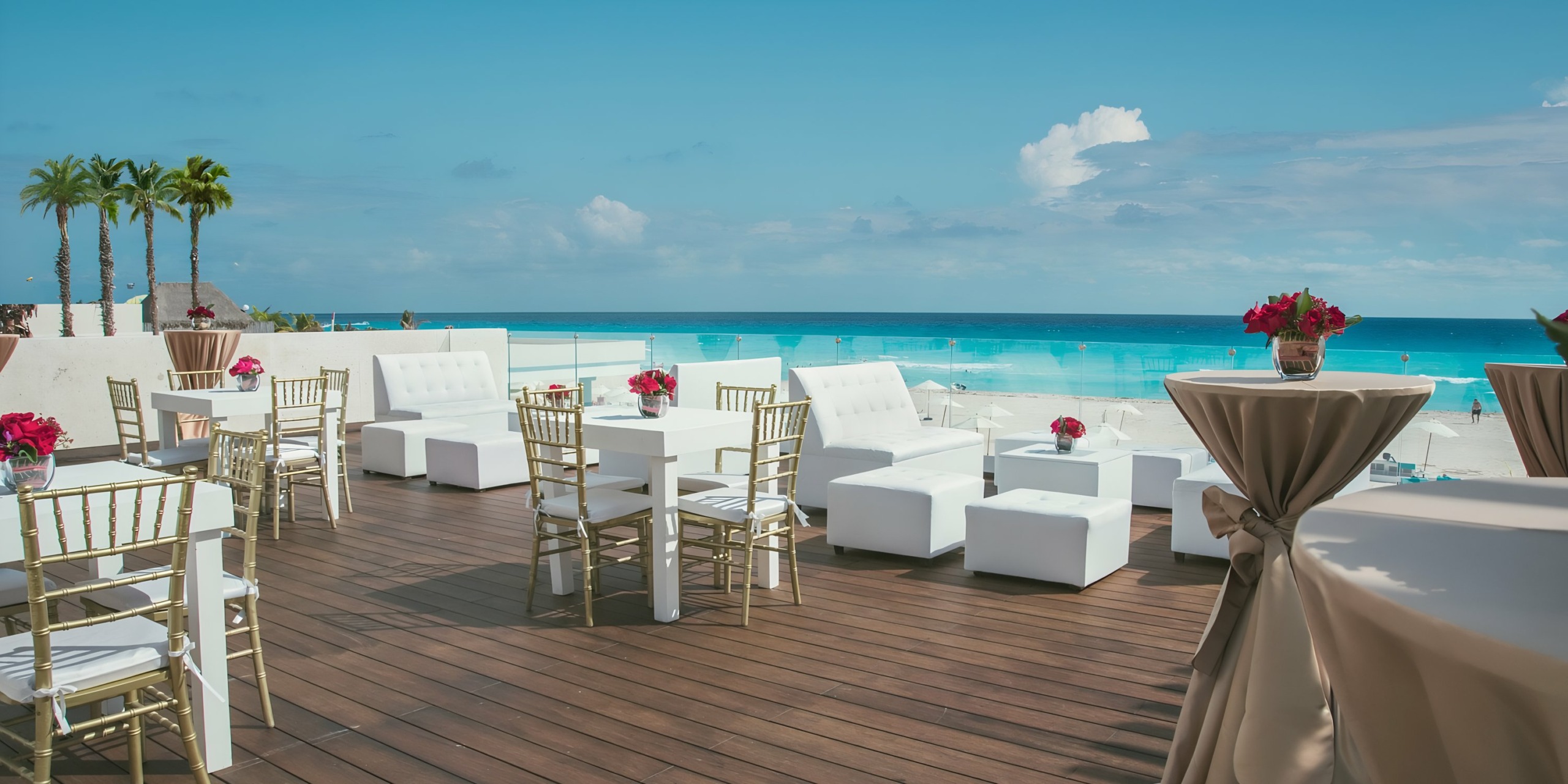An outdoor event setup at Iberostar Selection Cancun with white chairs and tables overlooking a calm blue sea under a clear sky.