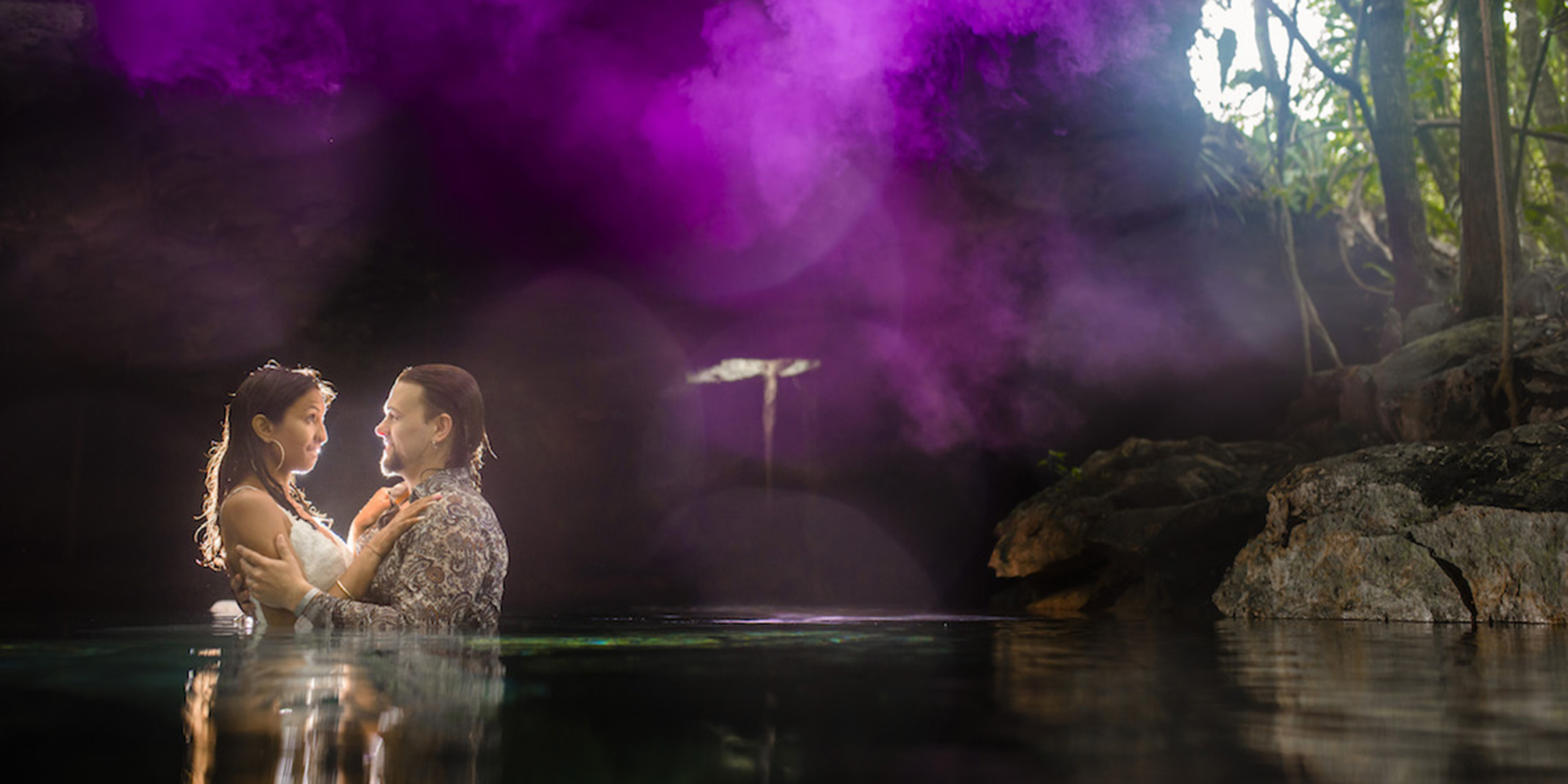 Jason and Priya embrace in the jungle in a pond
