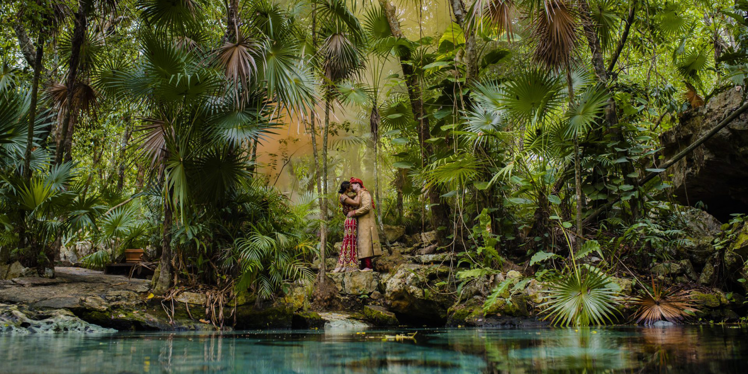 Jason and Priya kiss in the jungle by a pond