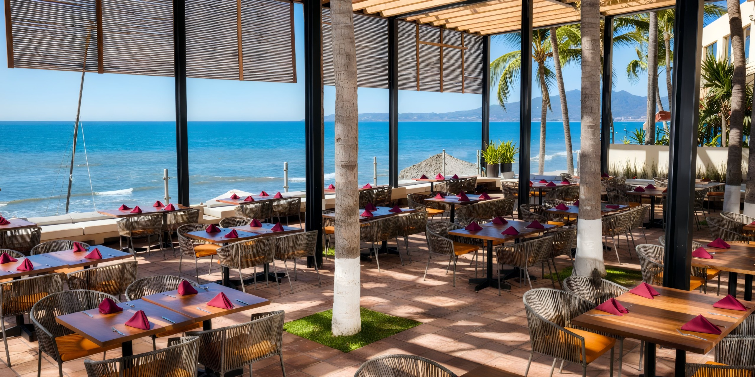 The outdoor restaurant at Krystal Grand Nuevo Vallarta features neatly arranged tables adorned with red napkins, offering scenic views of the ocean and distant mountains, with palm trees thoughtfully spaced throughout the seating area.