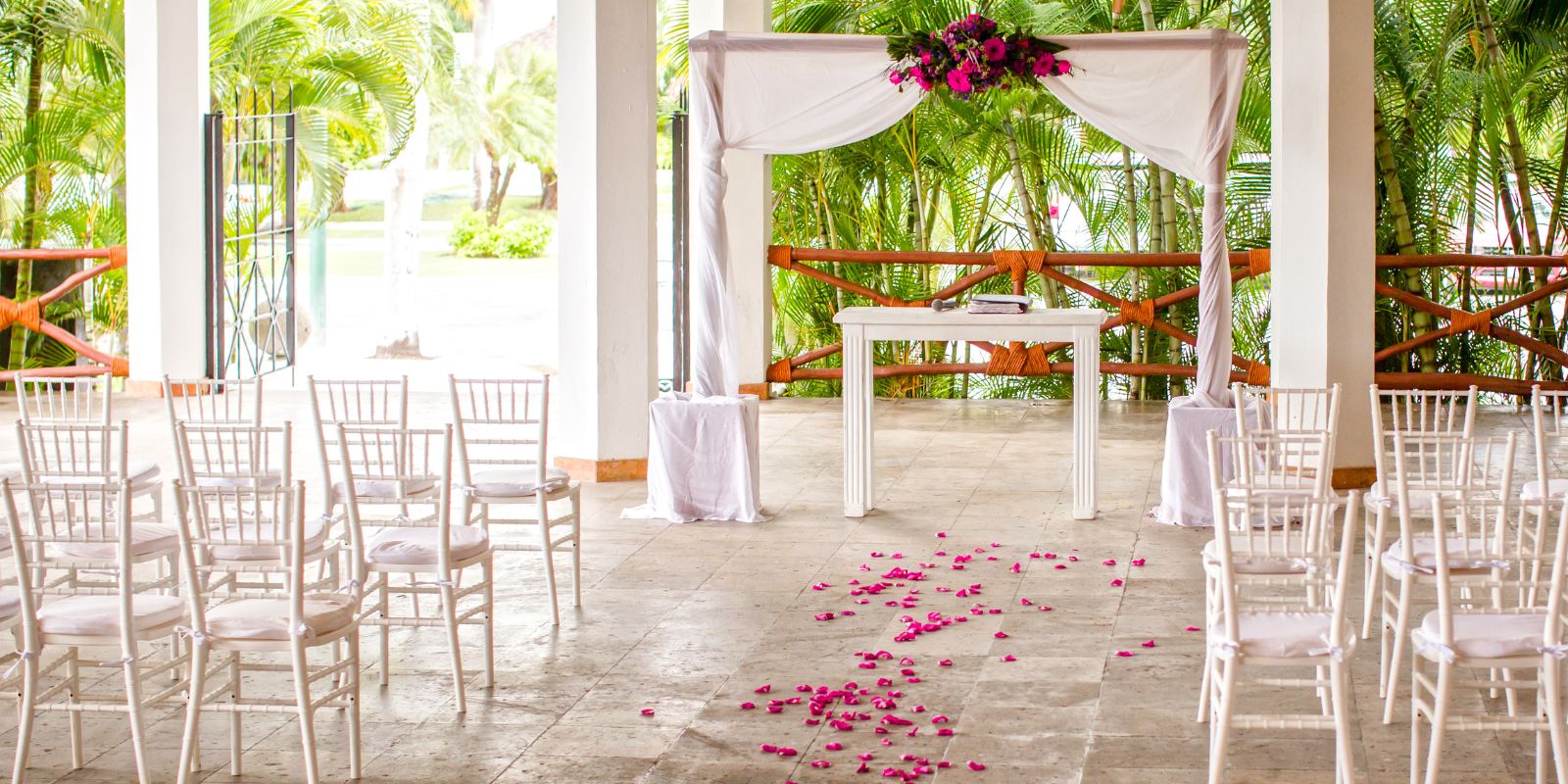 A wedding ceremony is set up with Marival Emotions chairs and pink petals.