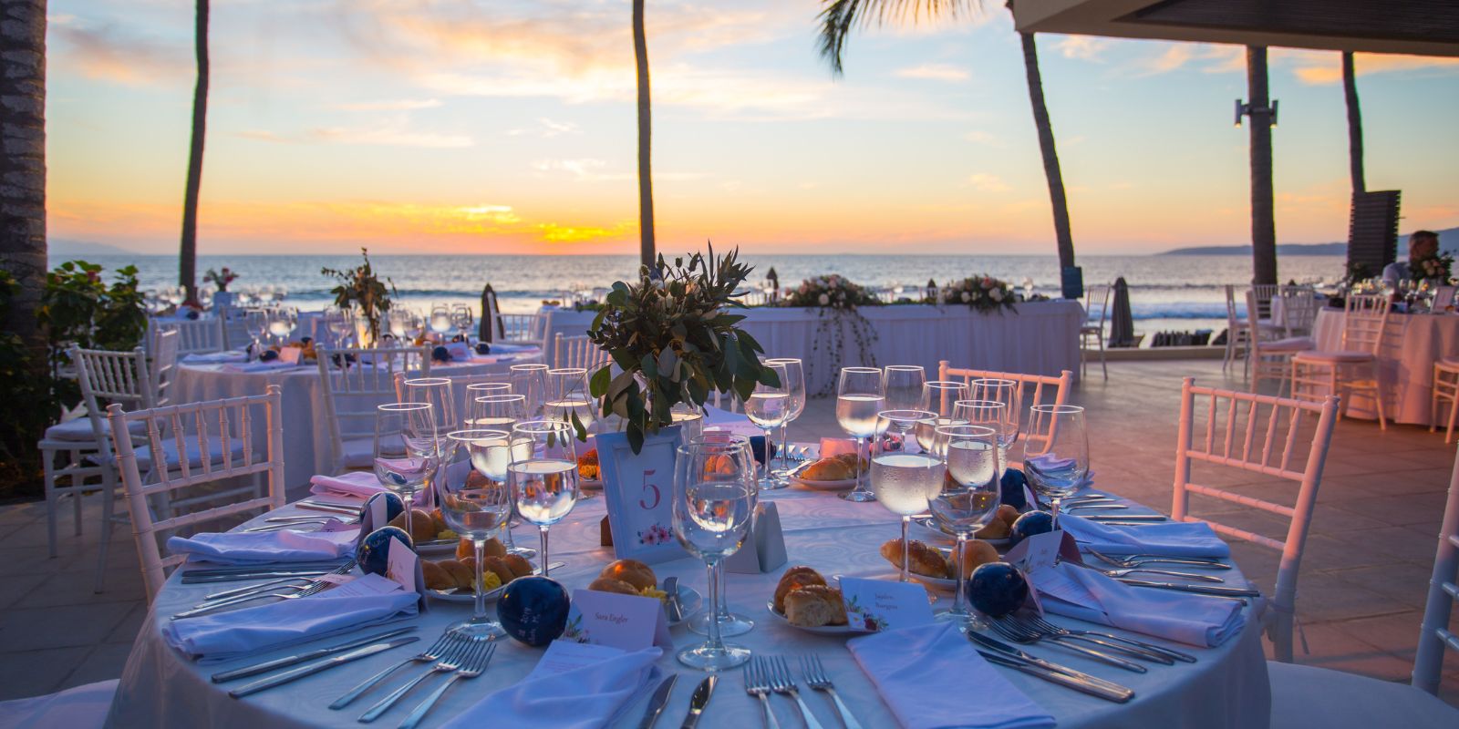 A Marival Emotions wedding reception set up on the beach at sunset.