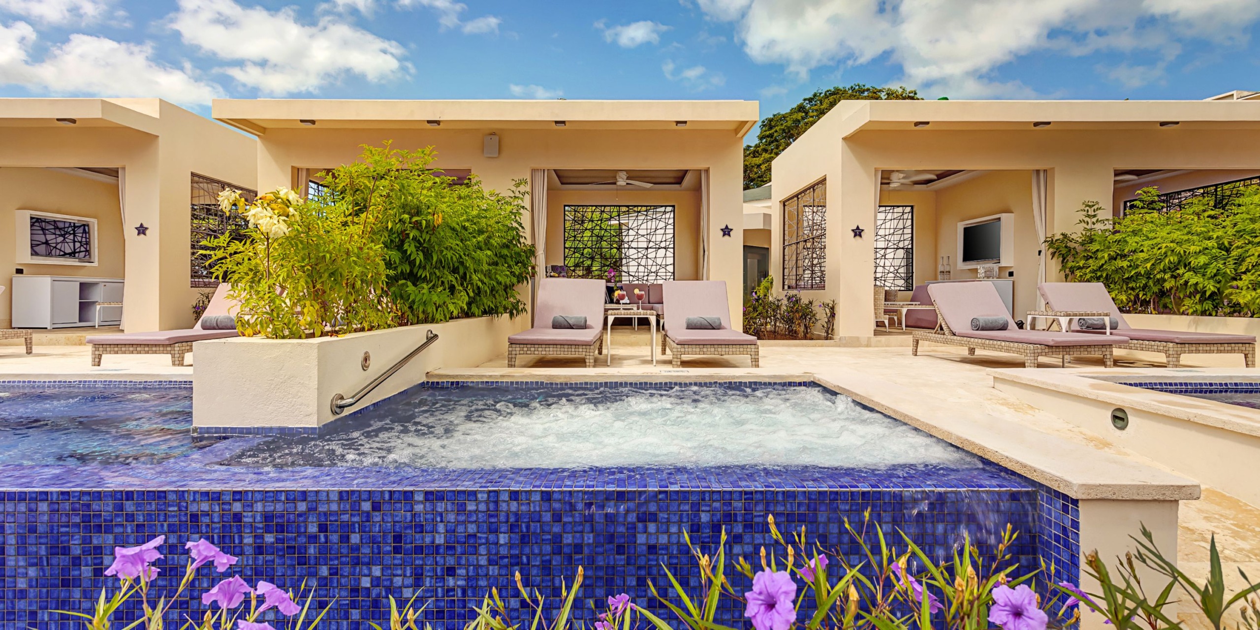 The Planet Hollywood Costa Rica features a jacuzzi with bubbling water in the foreground, surrounded by lounge chairs and private cabanas, all set under a cloudy sky.