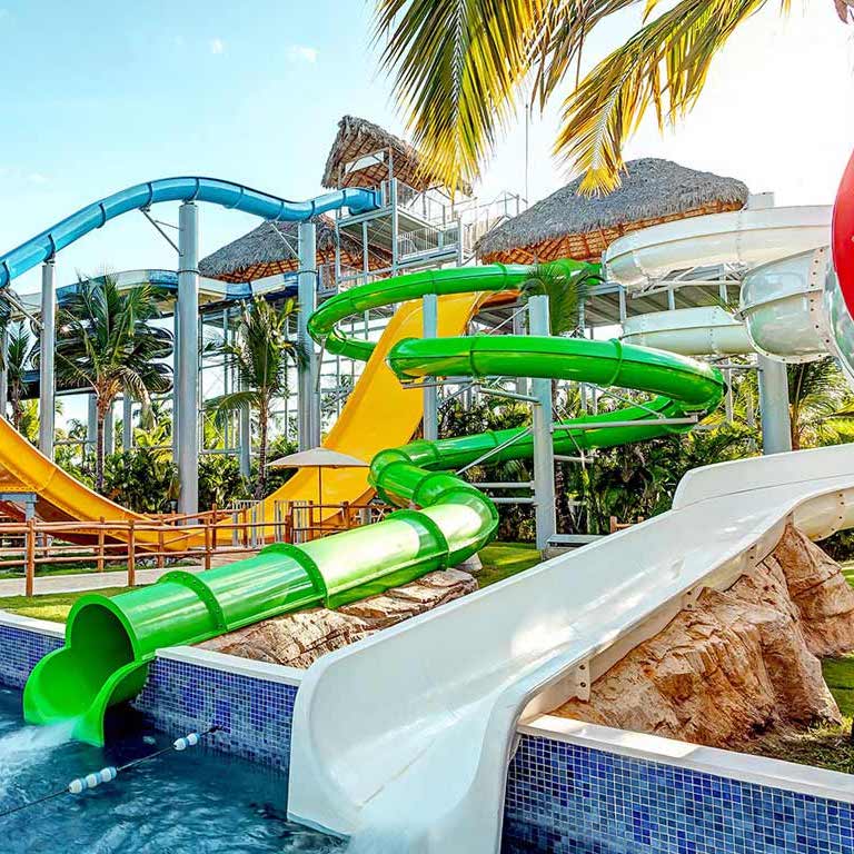 Colorful water slides surrounded by palm trees at Royalton Splash Punta Cana, perfect for destination weddings, on a sunny day.