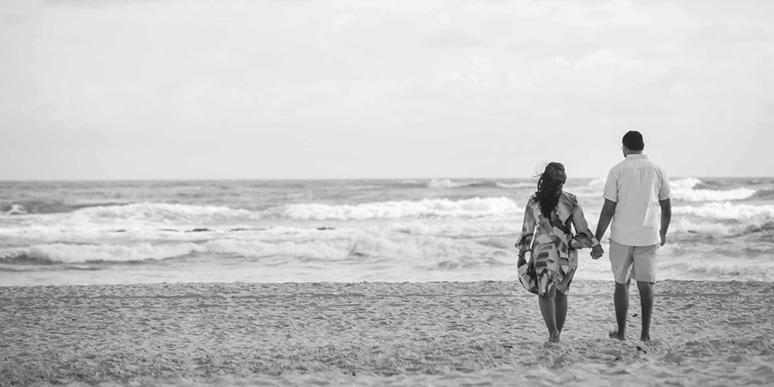 Shruti and Nikhil walk together hand-in-hand on the beach