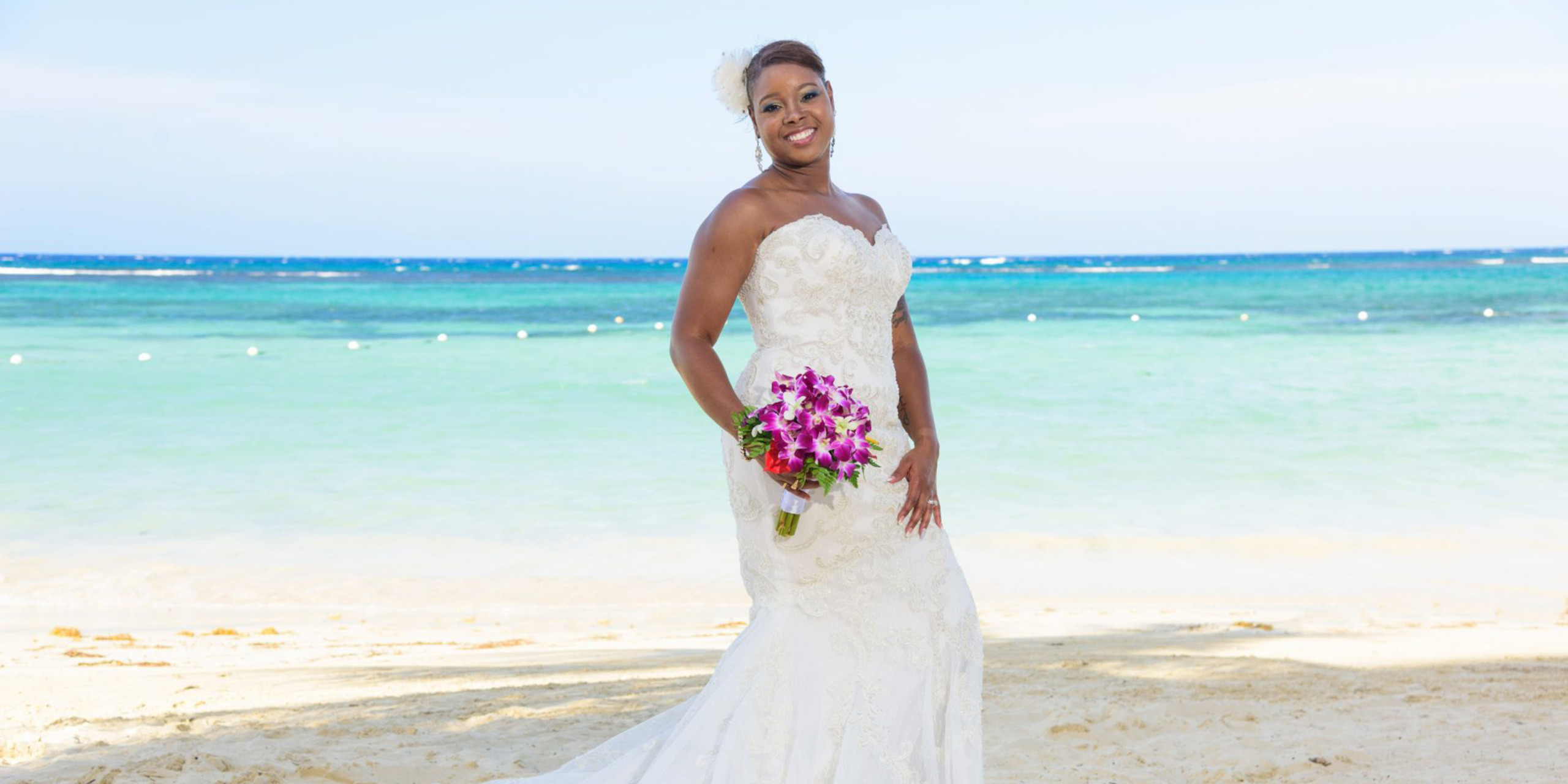 Tonya poses on the beach with her beautiful wedding dress and bouquet during the Tonya and Omar wedding