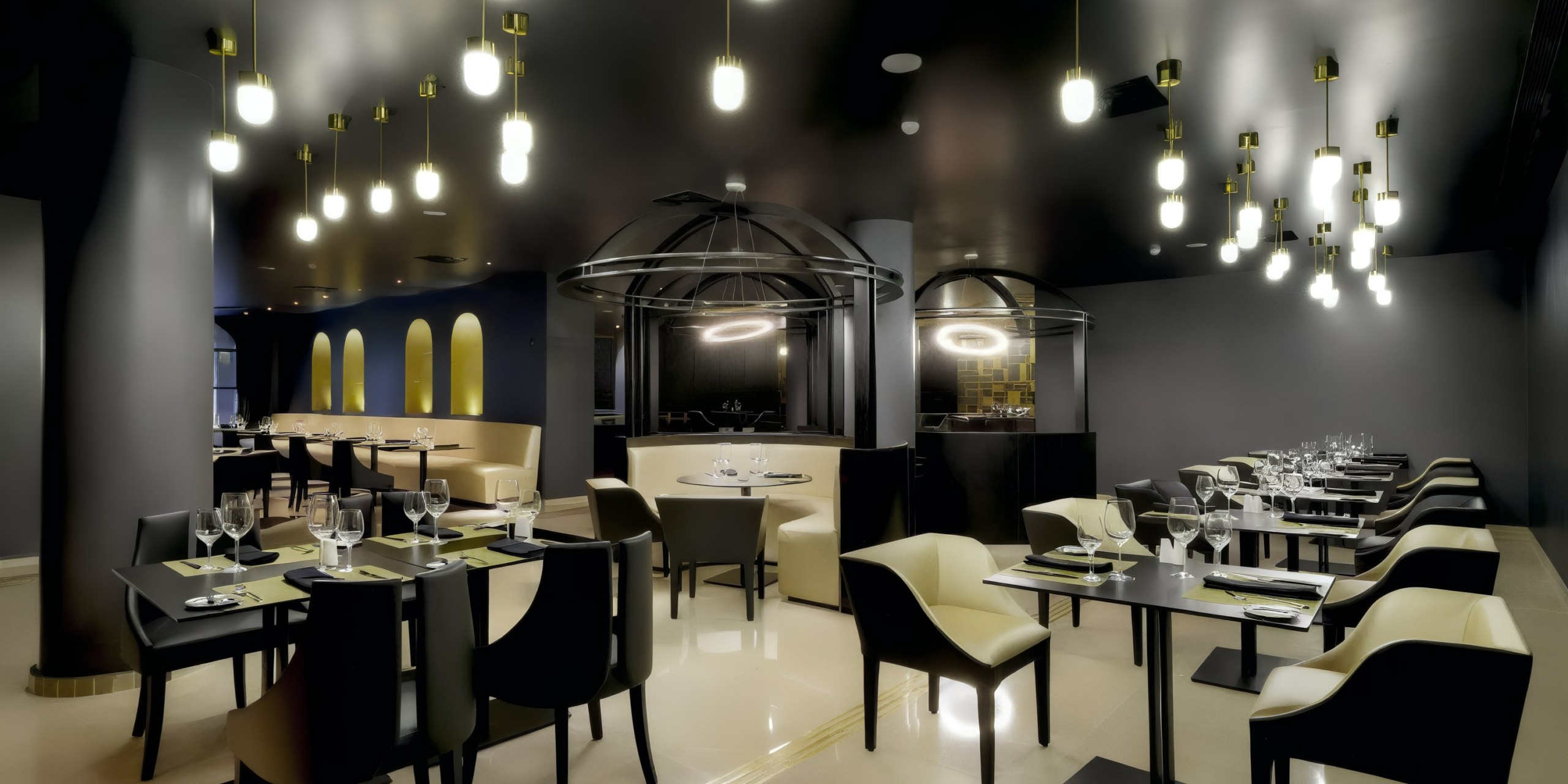 The modern restaurant interior features rows of tables and chairs, dim lighting, and contemporary decor. The space is illuminated by TRS Yucatan hanging lights.