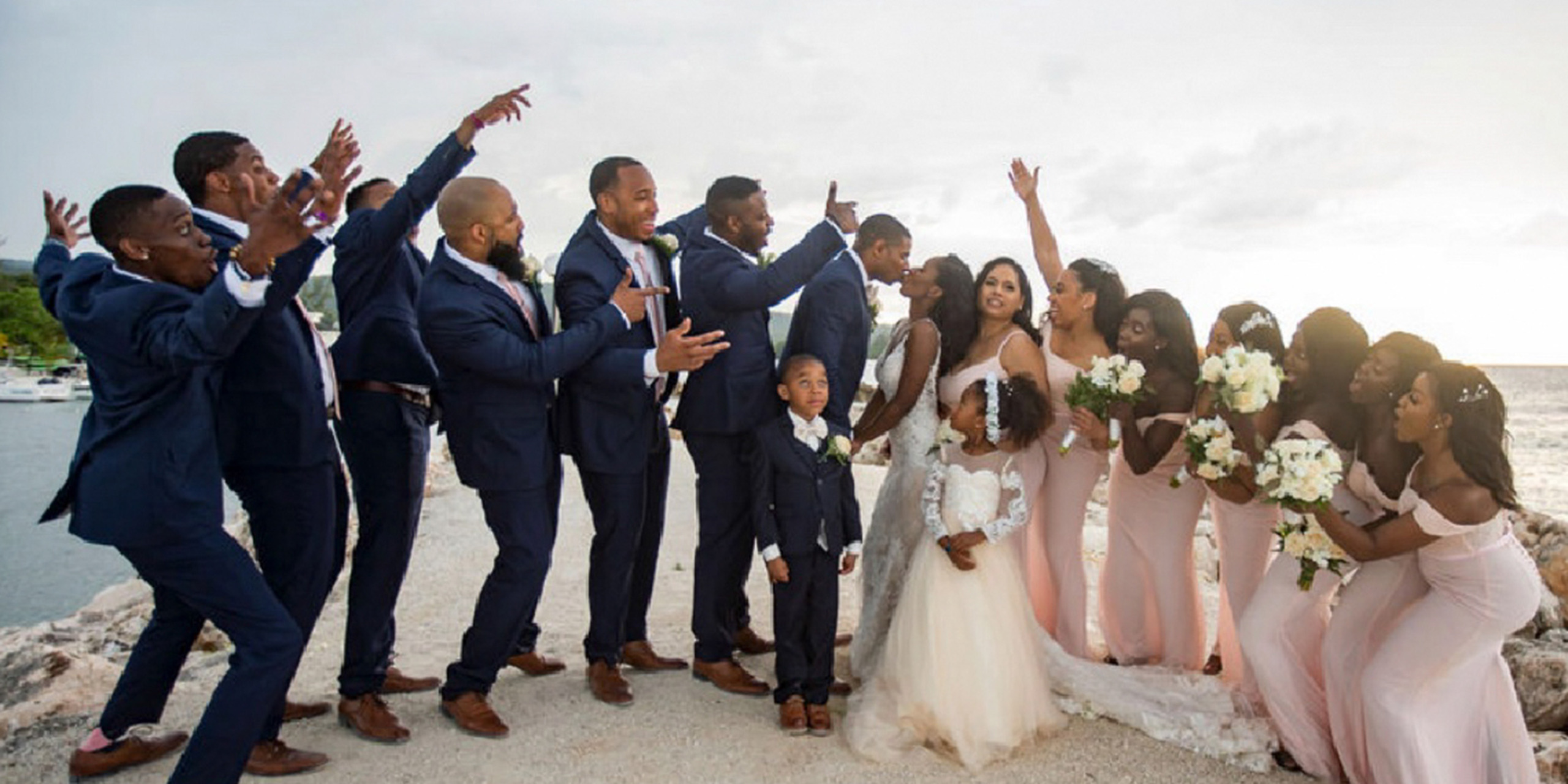 The entire wedding party groomsmen and bridesmaids celebrate at Wokie and James kiss