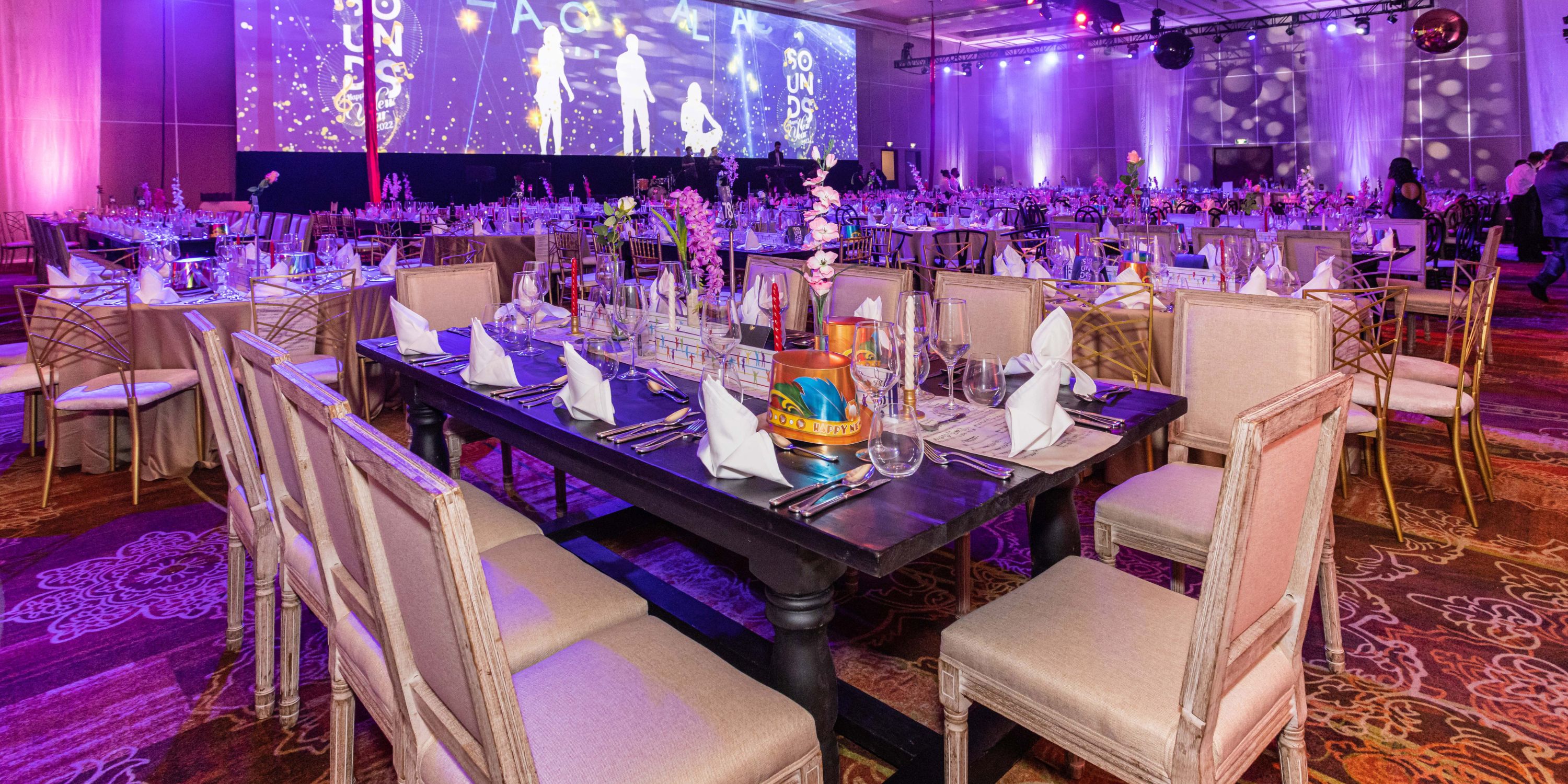 Beach Palace Cancun set up for a destination wedding with decorated tables, chairs, and a large screen.