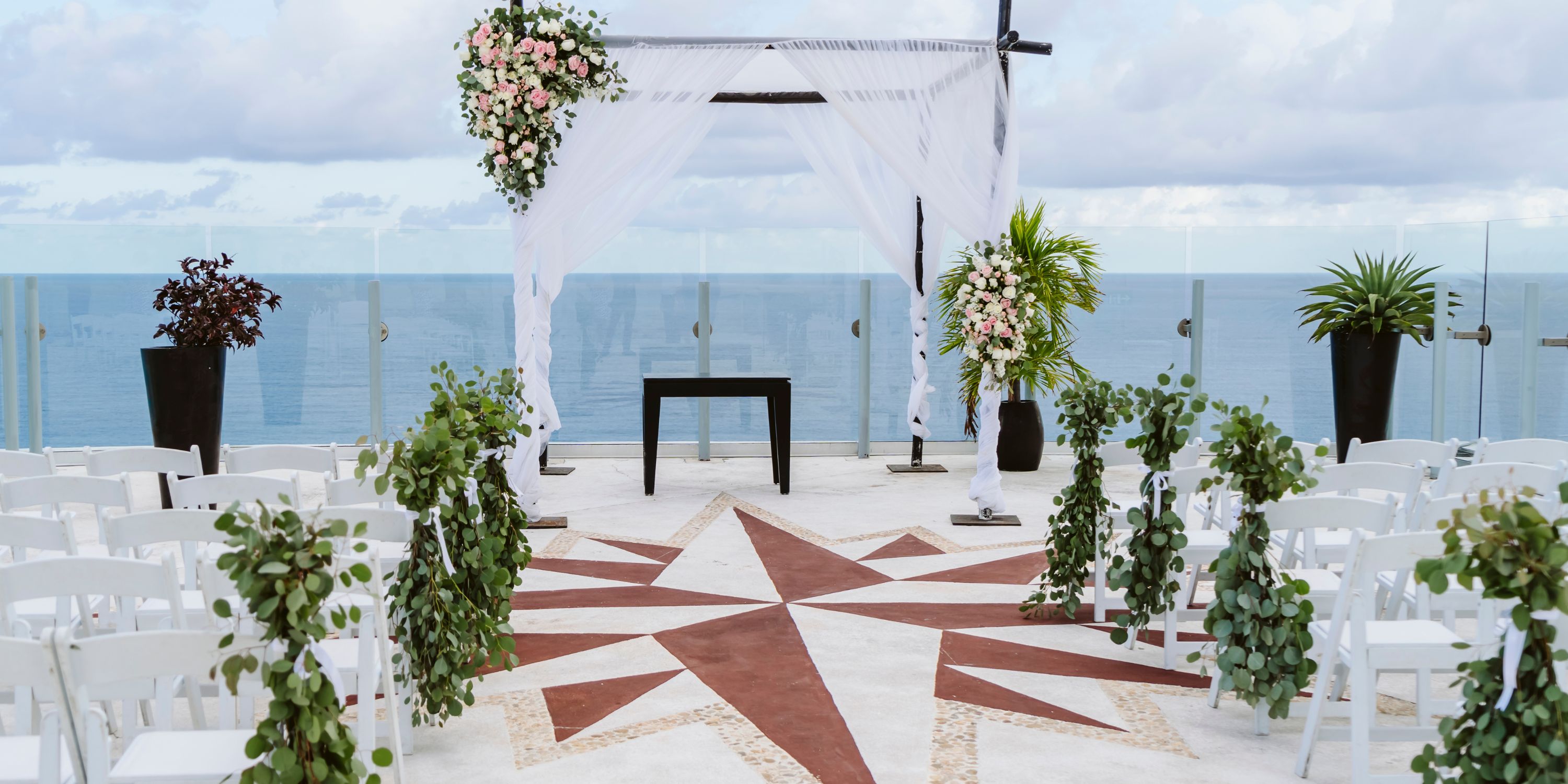 Beach Palace Cancun destination wedding setup with white chairs and floral altar decor by the ocean.