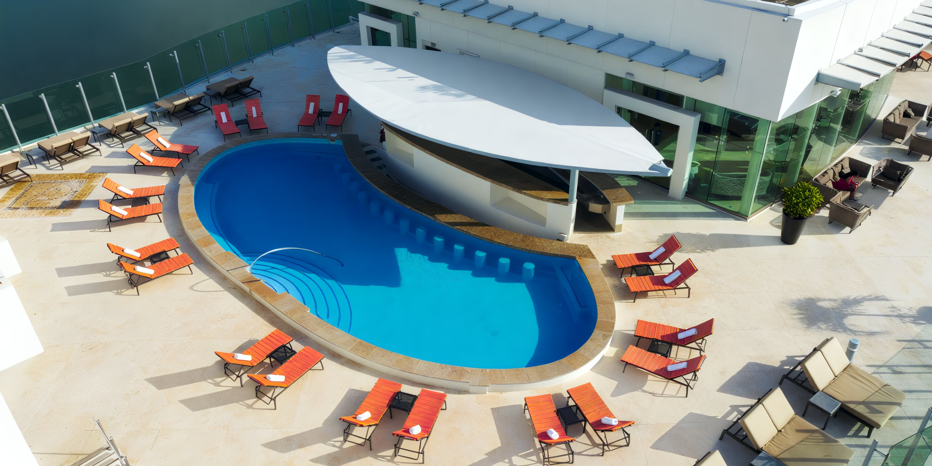 A breathtaking aerial view captures the oval pool of Beach Palace Cancun, surrounded by red loungers and the pristine white architecture—a perfect setting for a destination wedding.