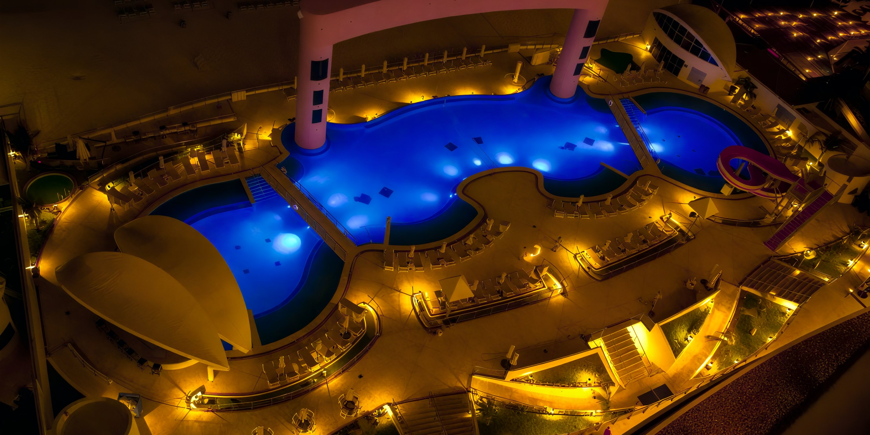 An aerial view showcases the illuminated pools and elegant lounge area of Beach Palace Cancun at night, making it an enchanting setting for a destination wedding.