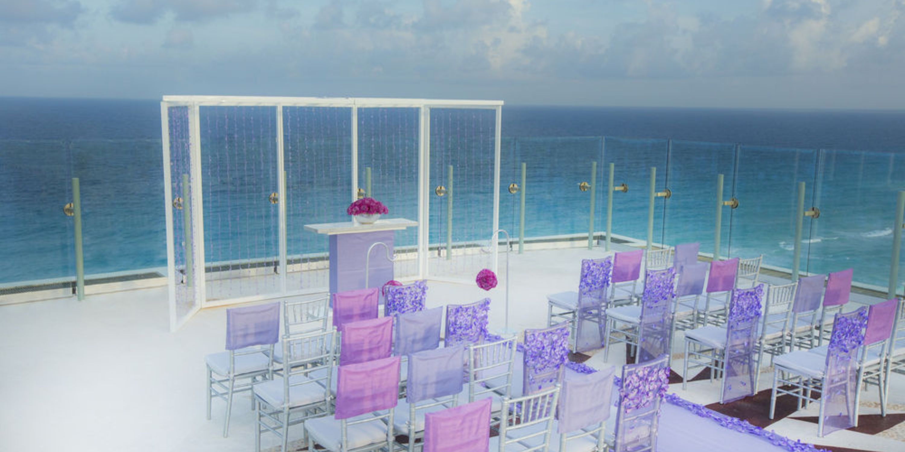 The Beach Palace Cancun offers a stunning setup with purple chairs overlooking the ocean, perfect for a destination wedding.