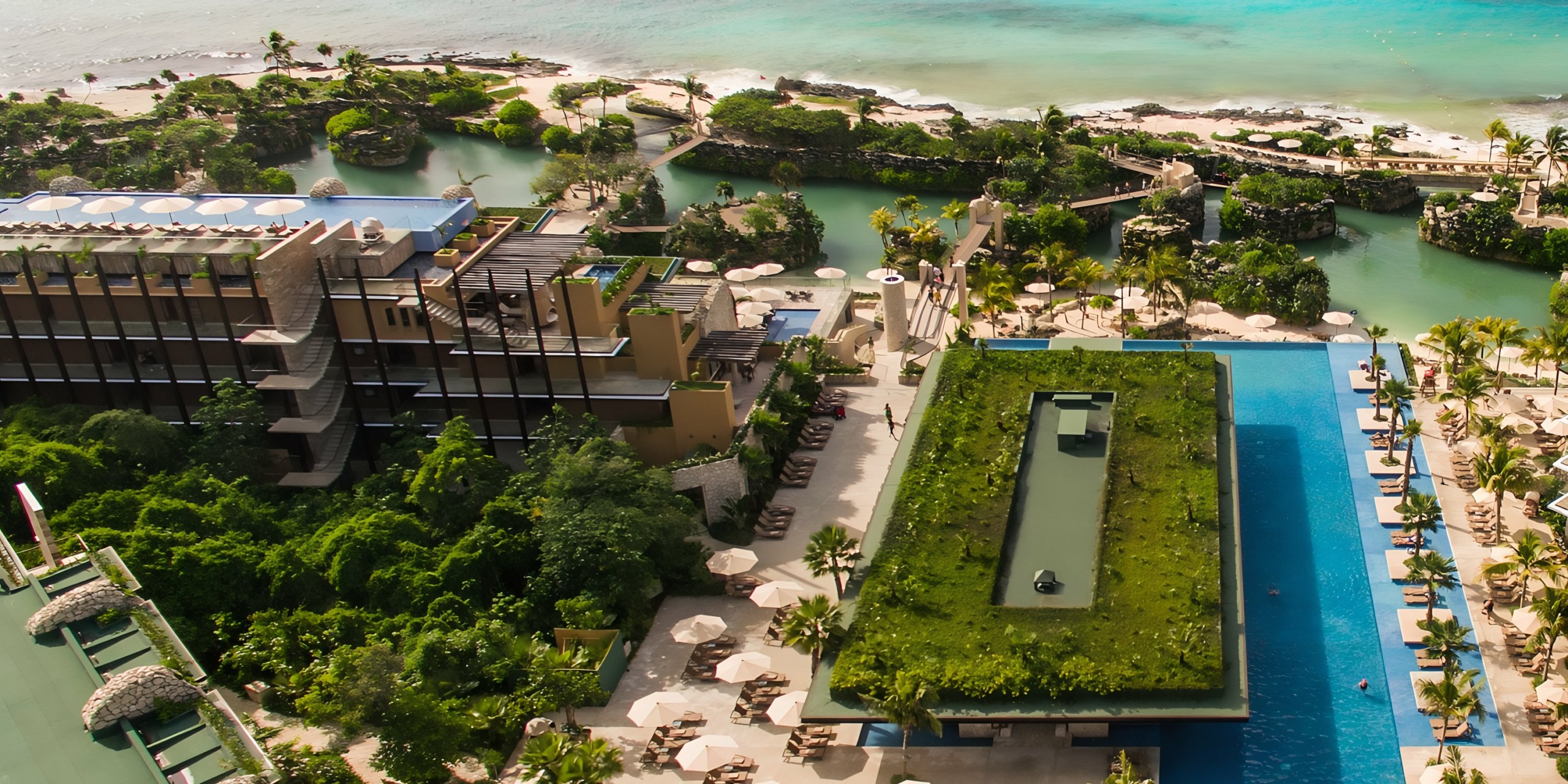 Aerial view of Hotel Xcaret with pools, palm trees, and beach areas, next to the ocean.
