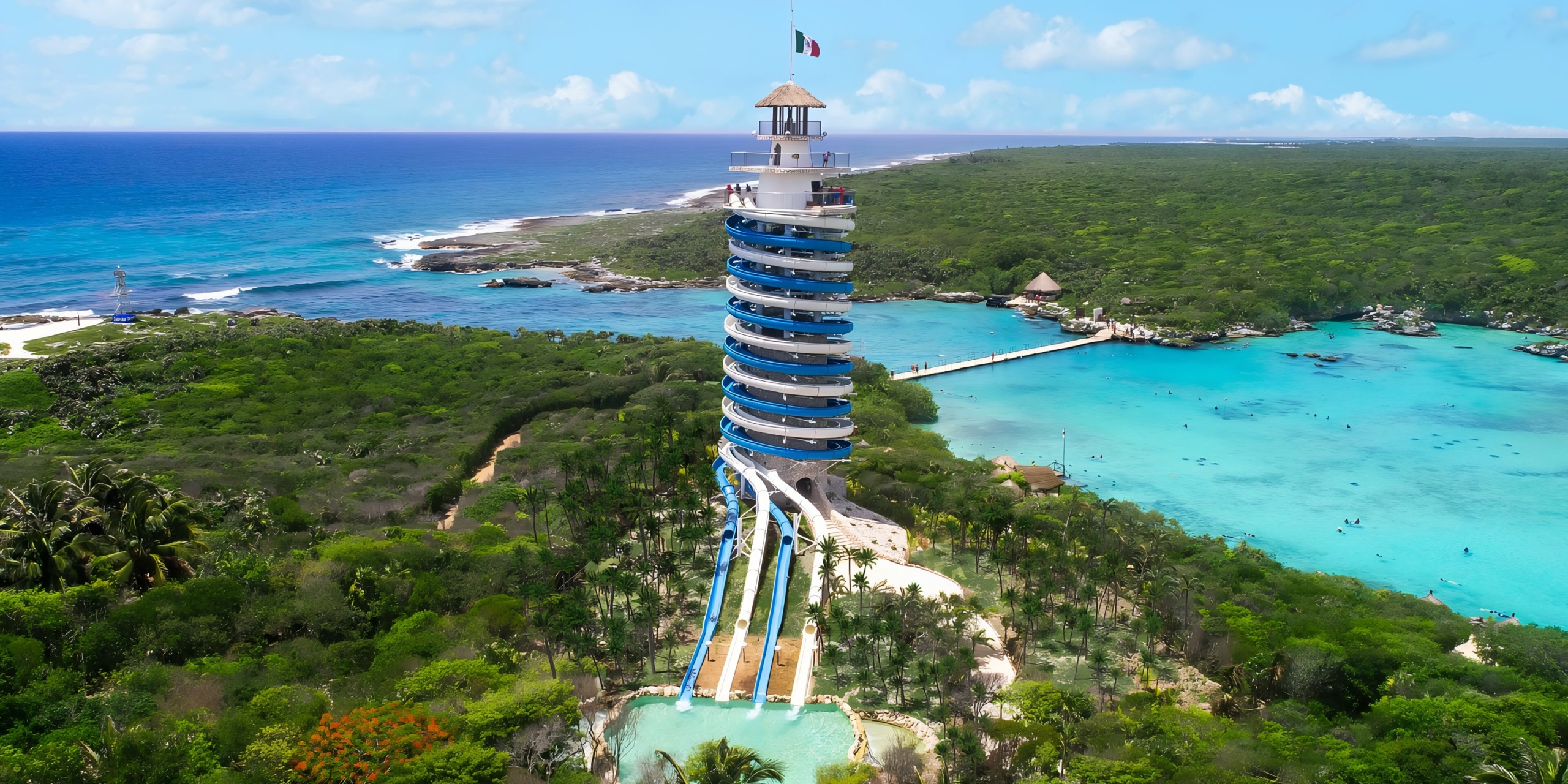 Sentence with product name: Aerial view of Hotel Xcaret overlooking a tropical beach lagoon with clear blue waters and lush greenery.