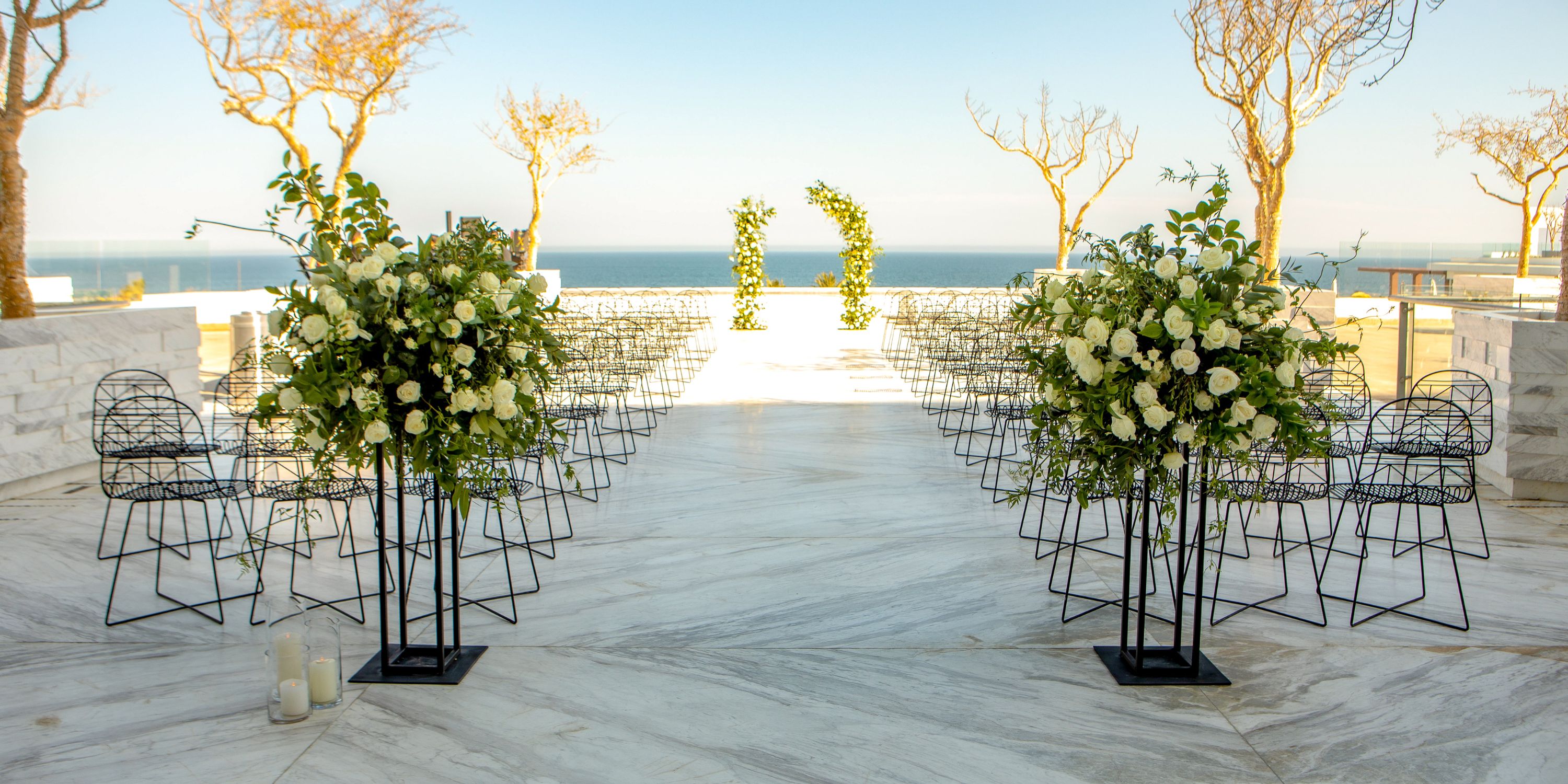 Destination wedding at Le Blanc Spa Resort Los Cabos with white flowers, metal chairs, and ocean views.