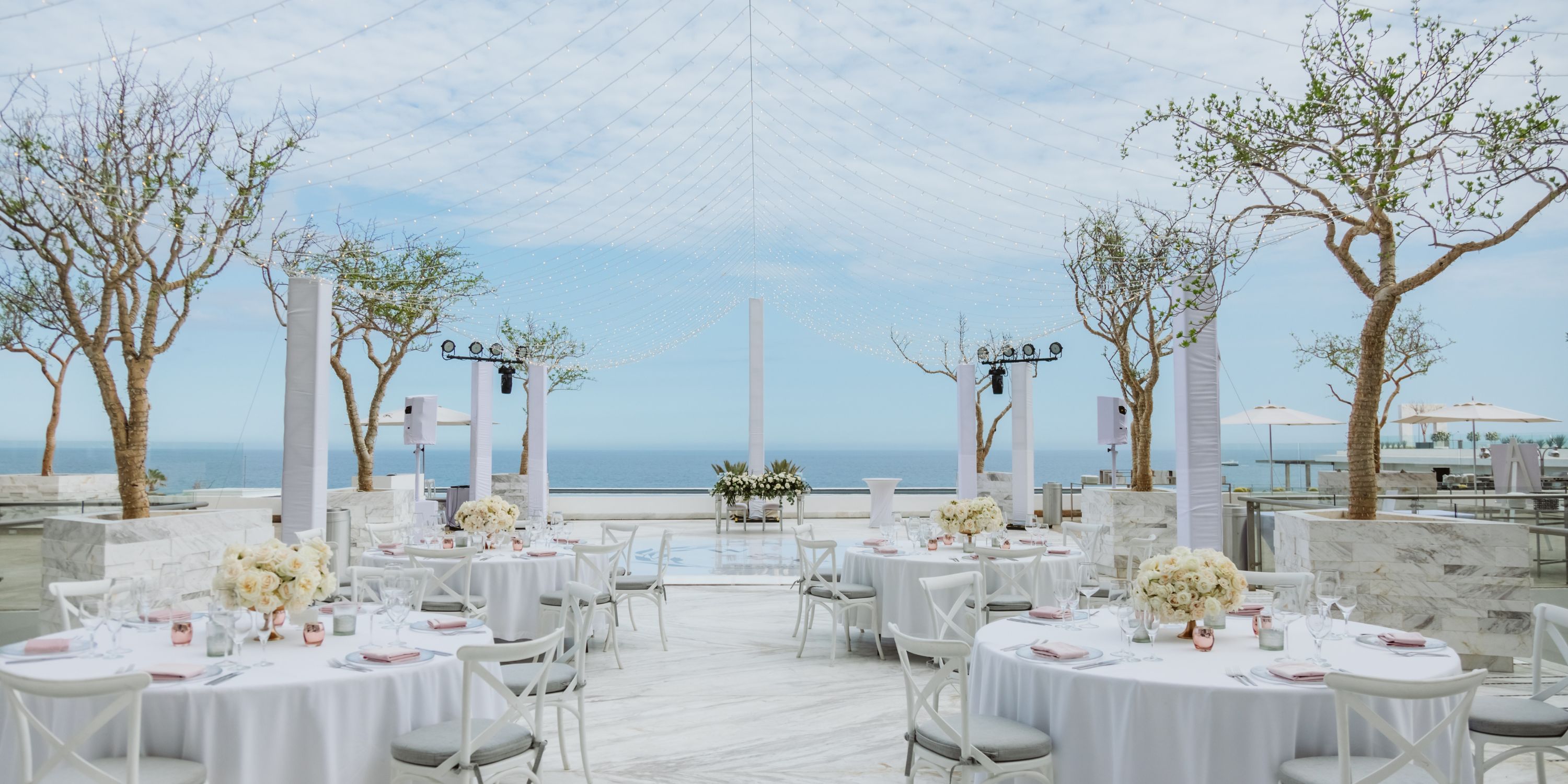 Destination wedding setup at Le Blanc Spa Resort Los Cabos with round tables, white chairs, and ocean views.