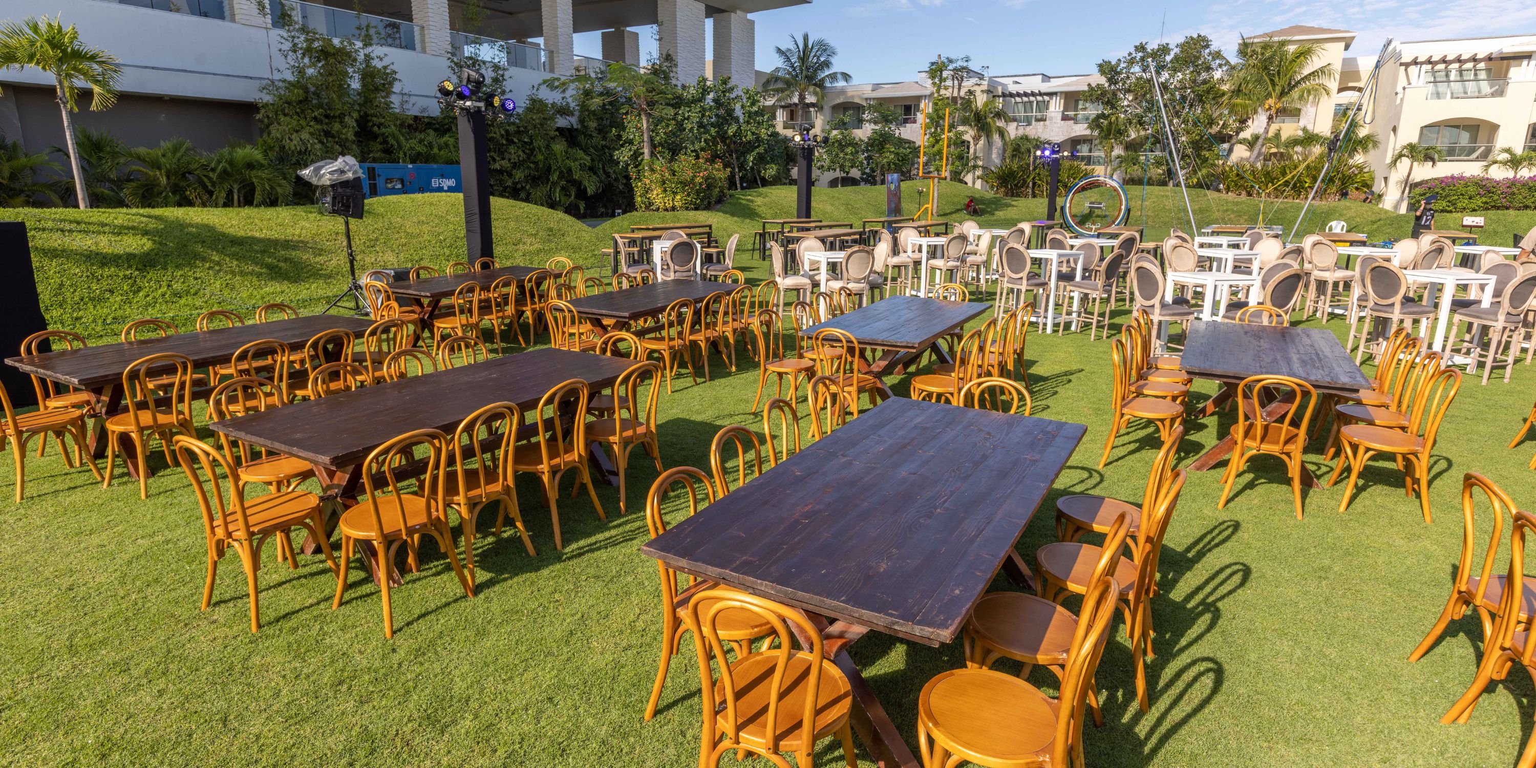 Moon Palace The Grand destination wedding setup with wooden tables and chairs on a grassy lawn.