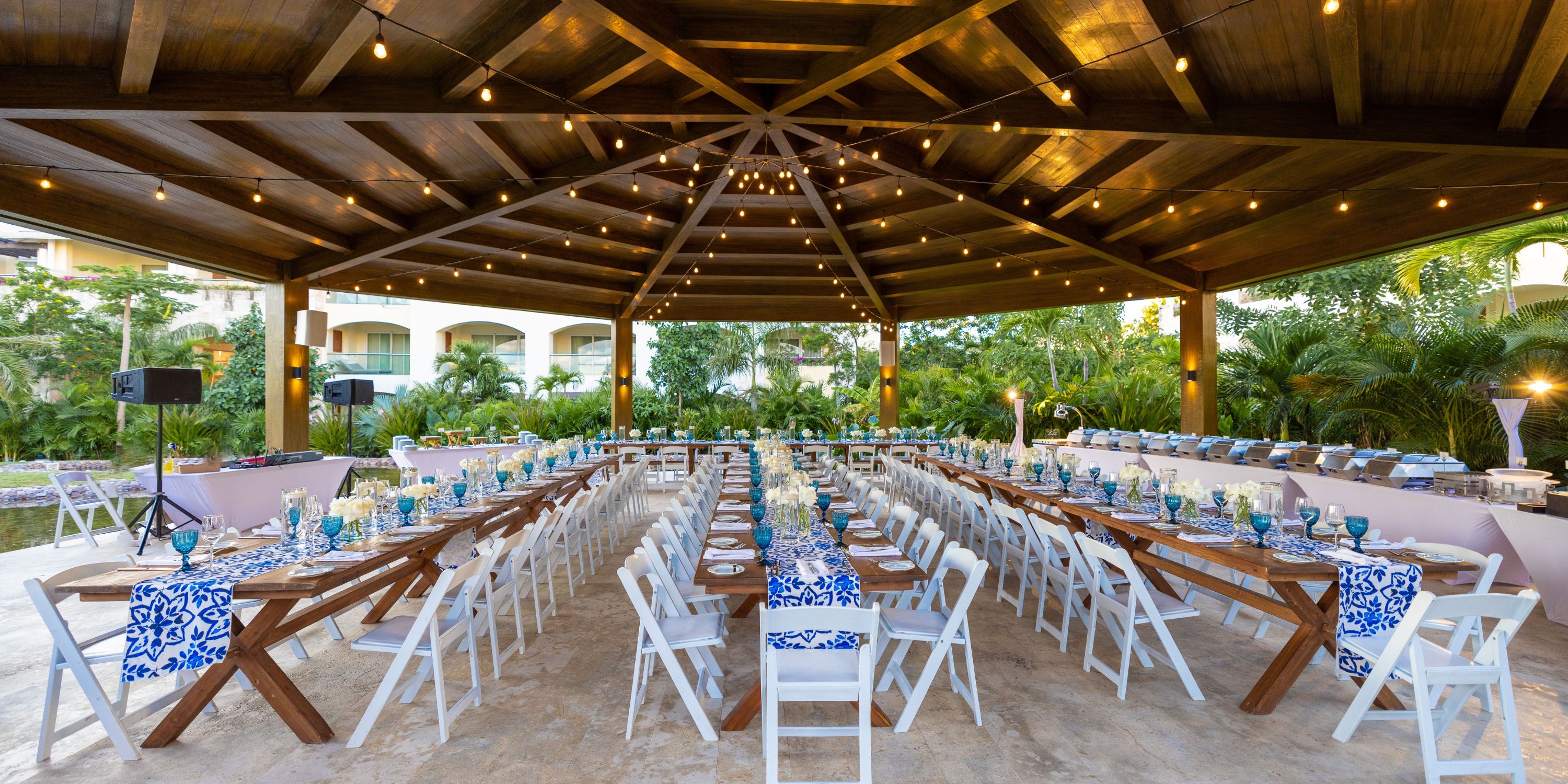 Moon Palace The Grand pavilion set for a destination wedding with banquet tables, white chairs, string lights, and blue decor.