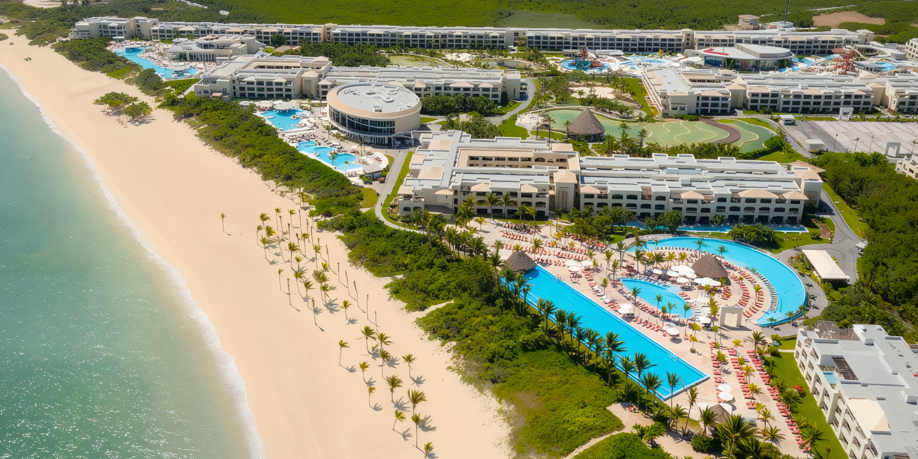 Aerial view of Moon Palace The Grand, a stunning beachfront resort featuring pools and lush greenery, perfect for a destination wedding.