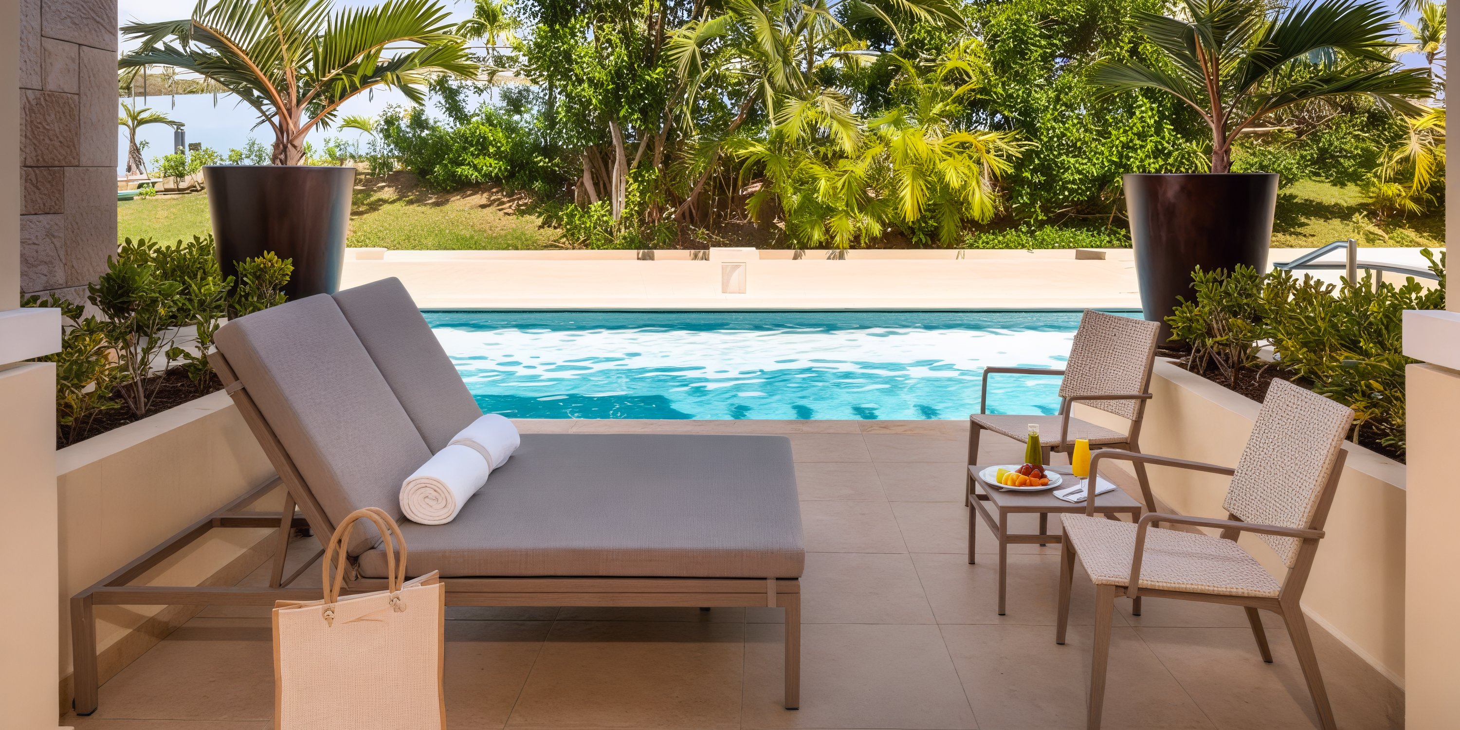 The poolside at Moon Palace The Grand offers an idyllic setting for a destination wedding, complete with chaise lounges, chairs, and towels perfectly framed by lush trees.