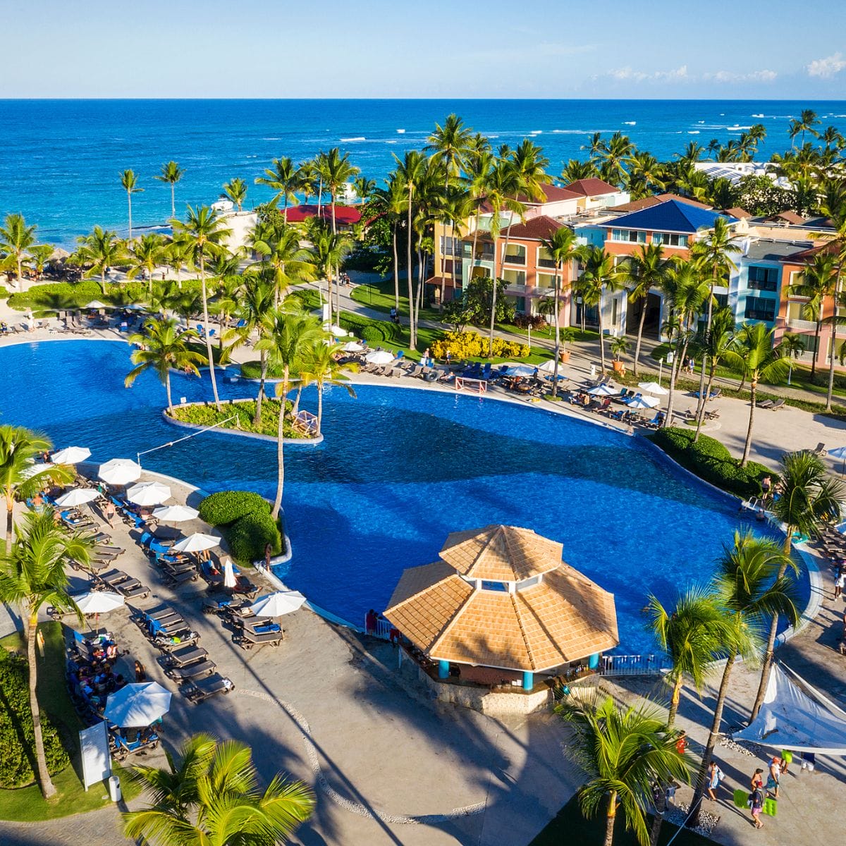 Ocean Blue and Sand is a destination wedding spot with a large pool, palms, and lounge chairs by the ocean.