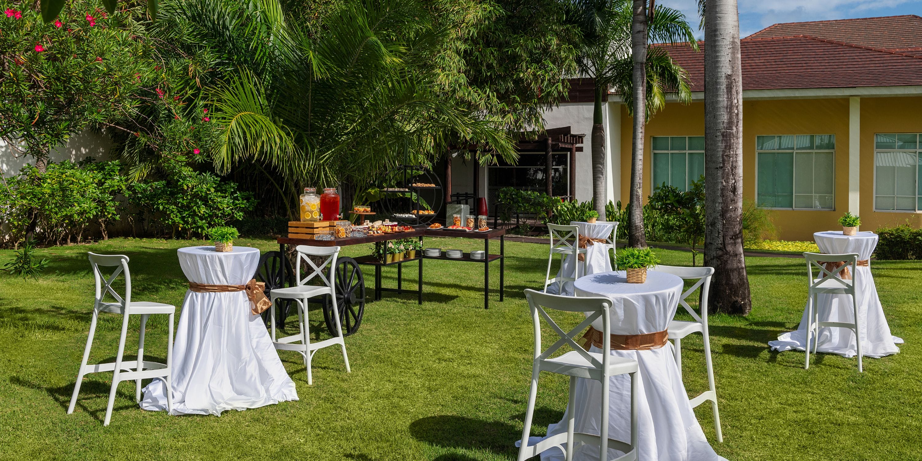 Destination wedding setup at Ocean Blue and Sand with cocktail tables and a buffet table on grass.