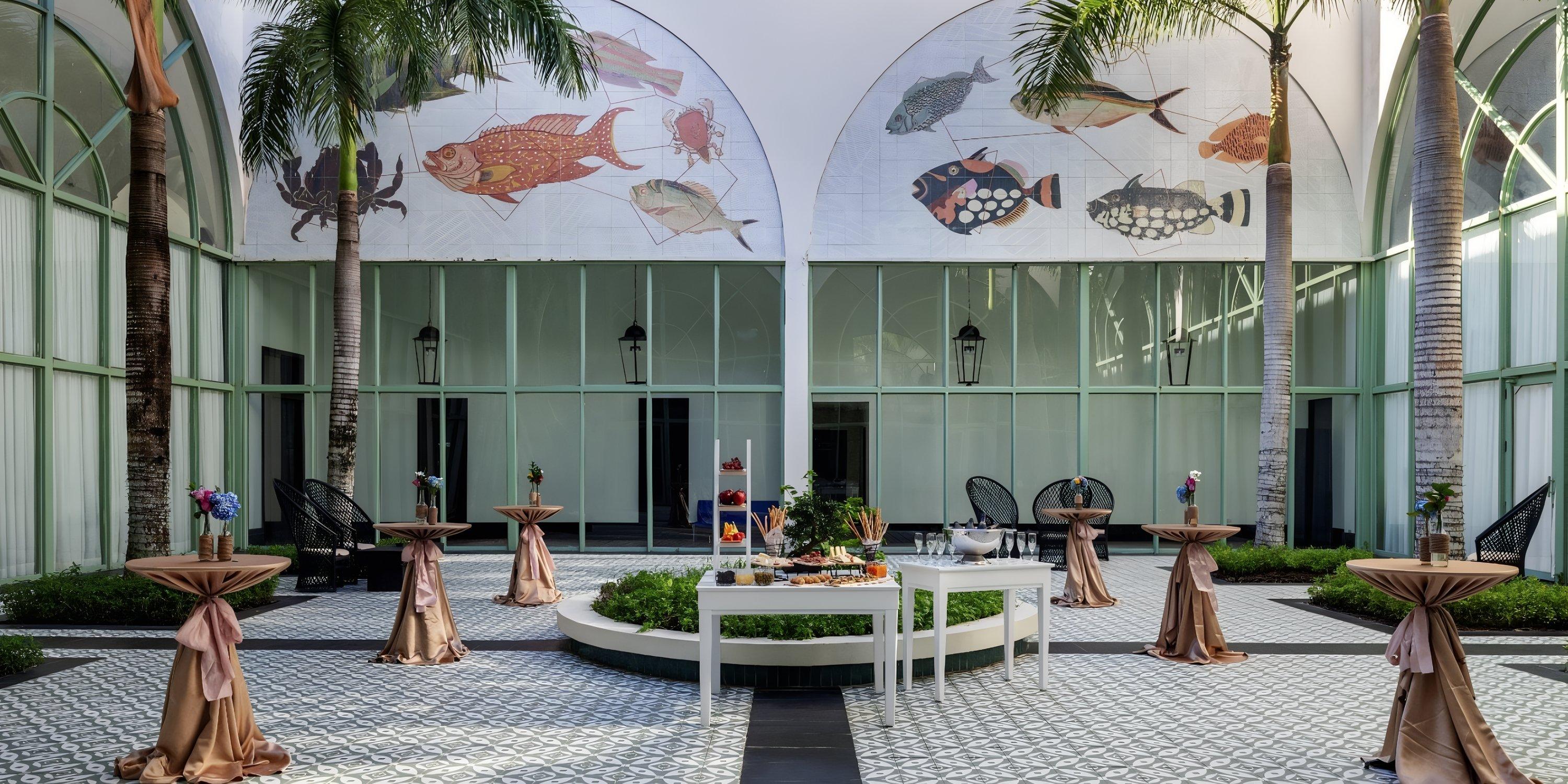 Ocean El Faro courtyard arranged for a destination wedding with cocktail tables, food table, and fish art.