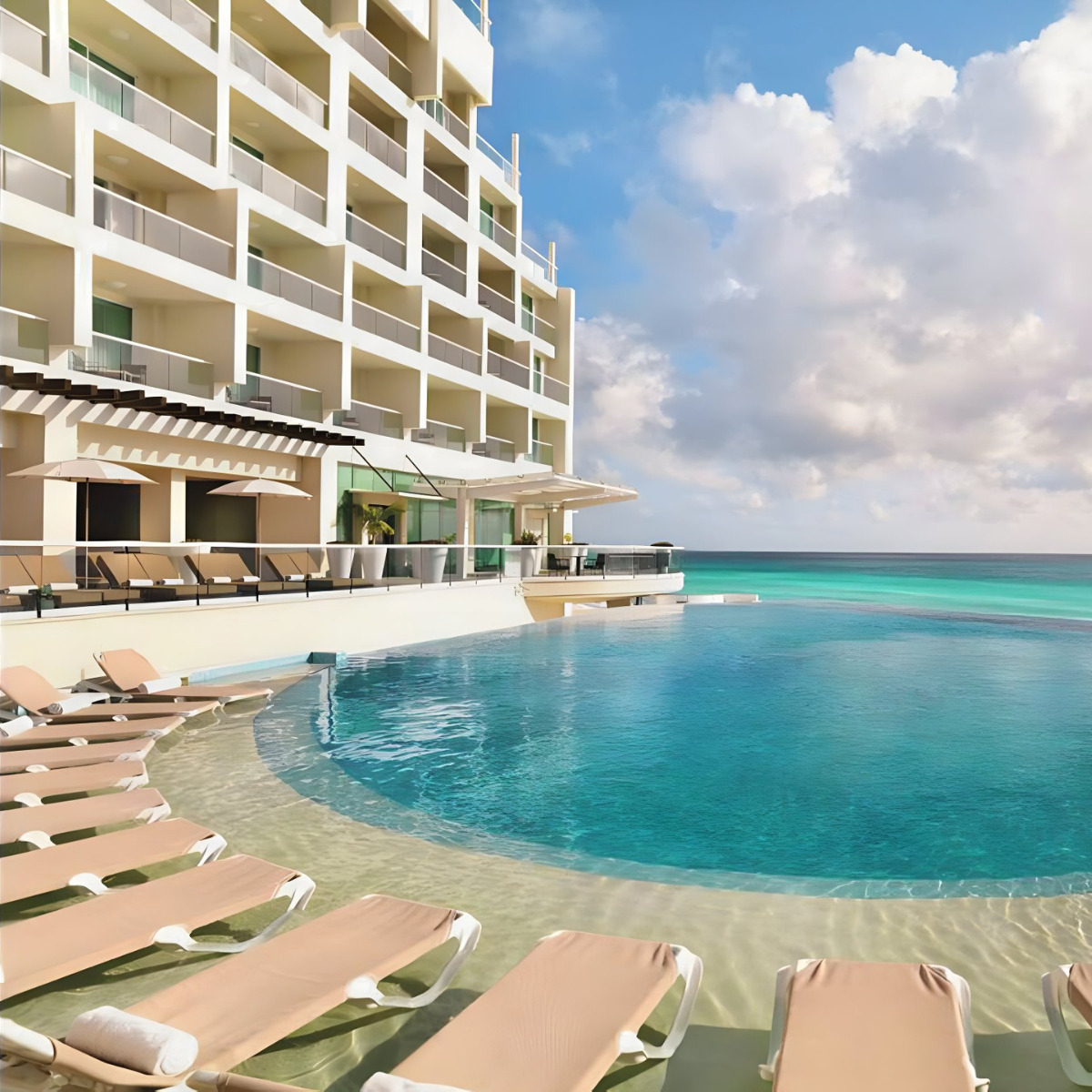 Sun Palace Cancun hotel with an infinity pool overlooking the ocean, perfect for destination weddings, featuring lined up sun loungers and a multi-story building facade.
