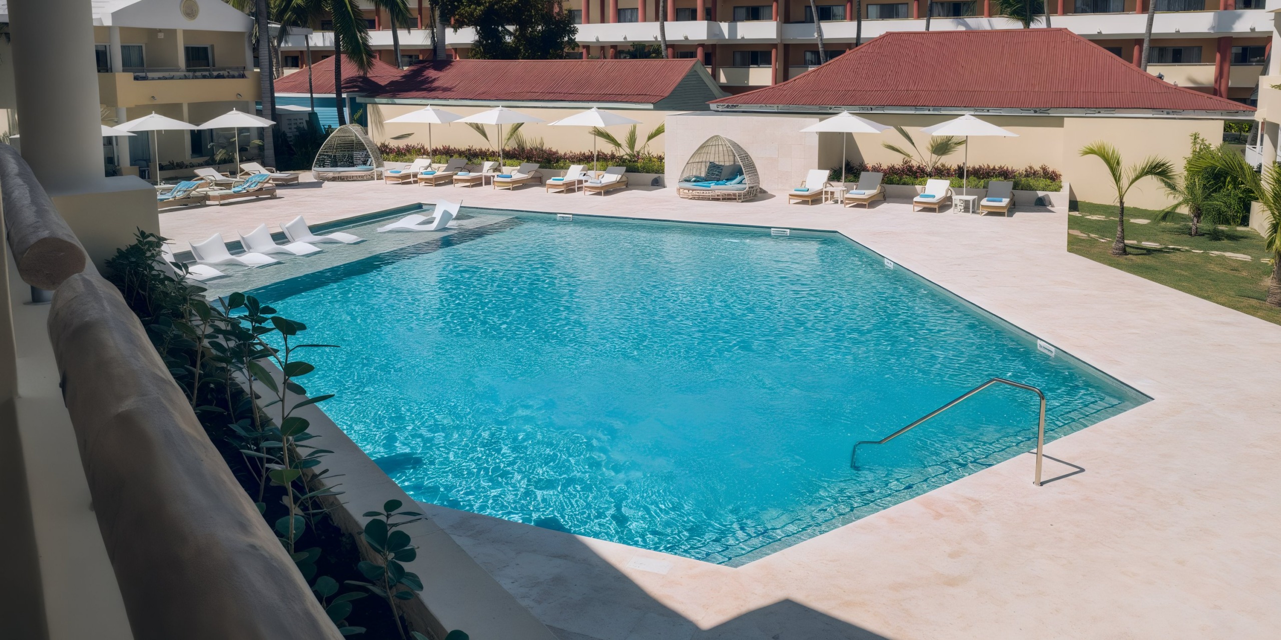Coral Level at Iberostar Selection Bavaro features a rectangular outdoor pool with lounge chairs and umbrellas on the deck, adjacent to the hotel building.