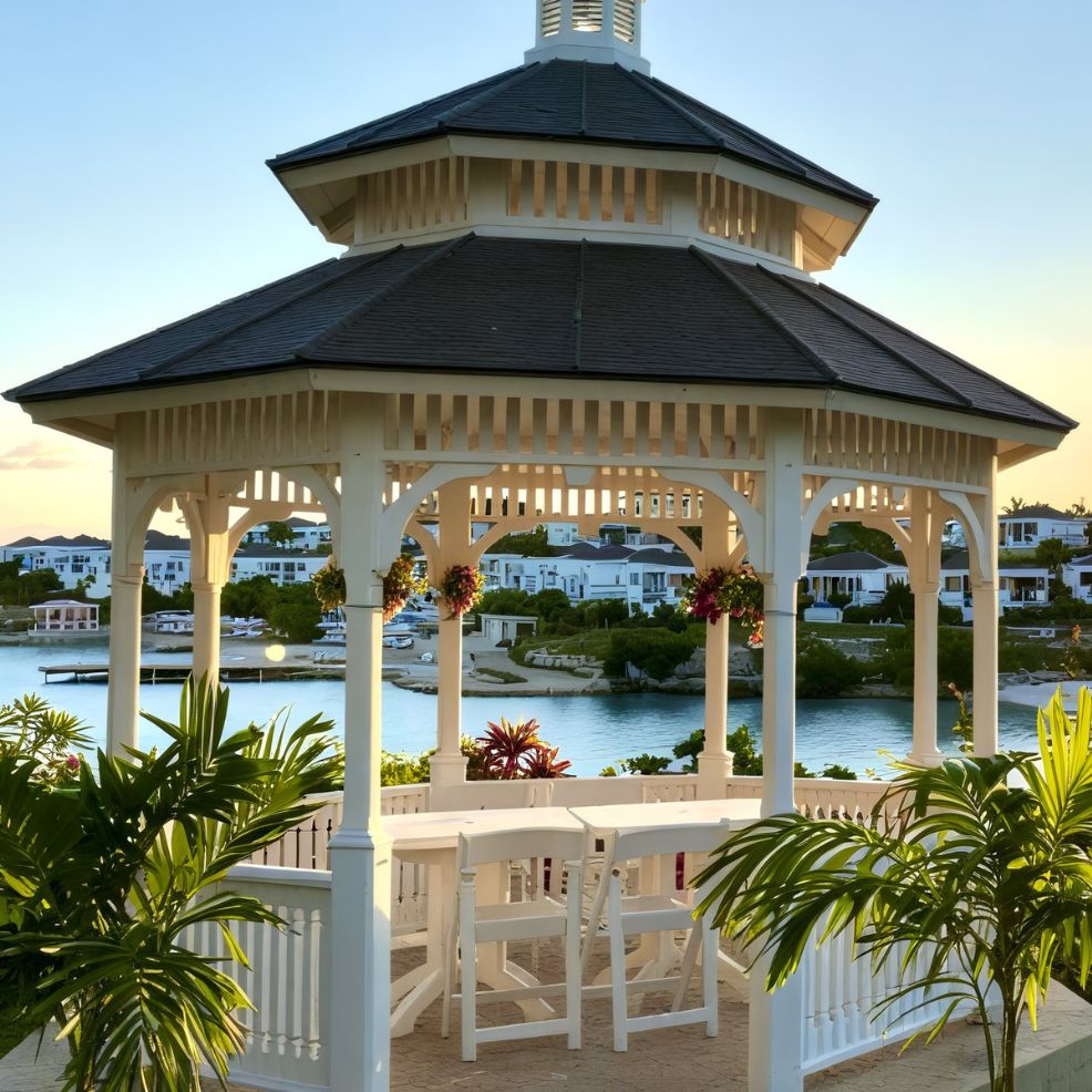 A white gazebo offers a picturesque setting for a destination wedding, overlooking a scenic waterfront with charming houses in the background.