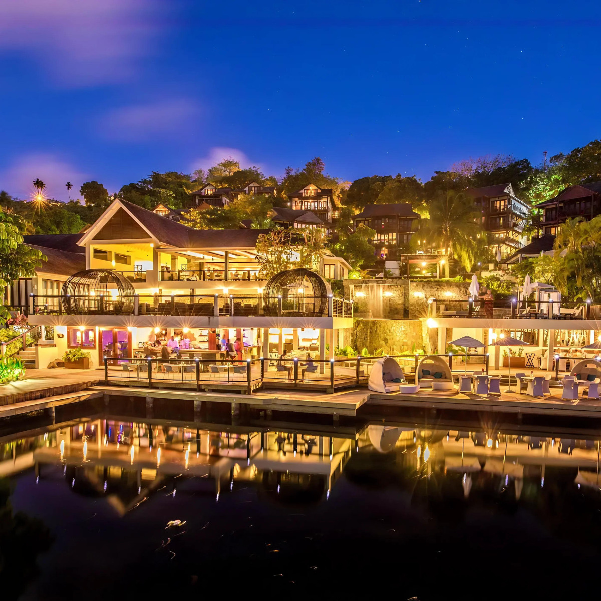 A wedding Zoetry Marigot Bay St. Lucia is lit up at night by the water.