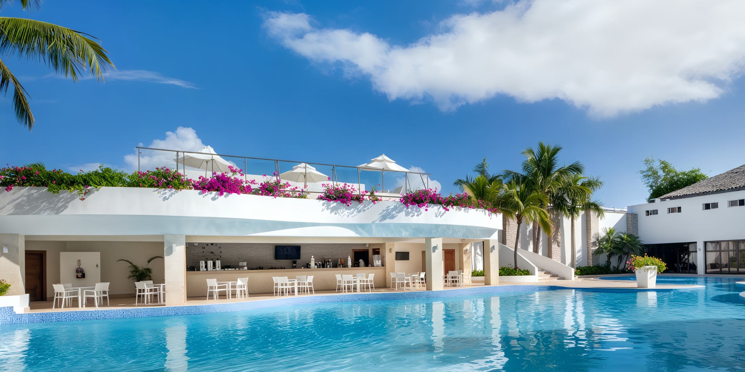 Experience the Viva Wyndham V Heavens - All-Inclusive Resort, Adults Only, featuring a poolside bar and seating area adorned with umbrellas, surrounded by lush tropical flowers and majestic palm trees, all beneath a clear blue sky.