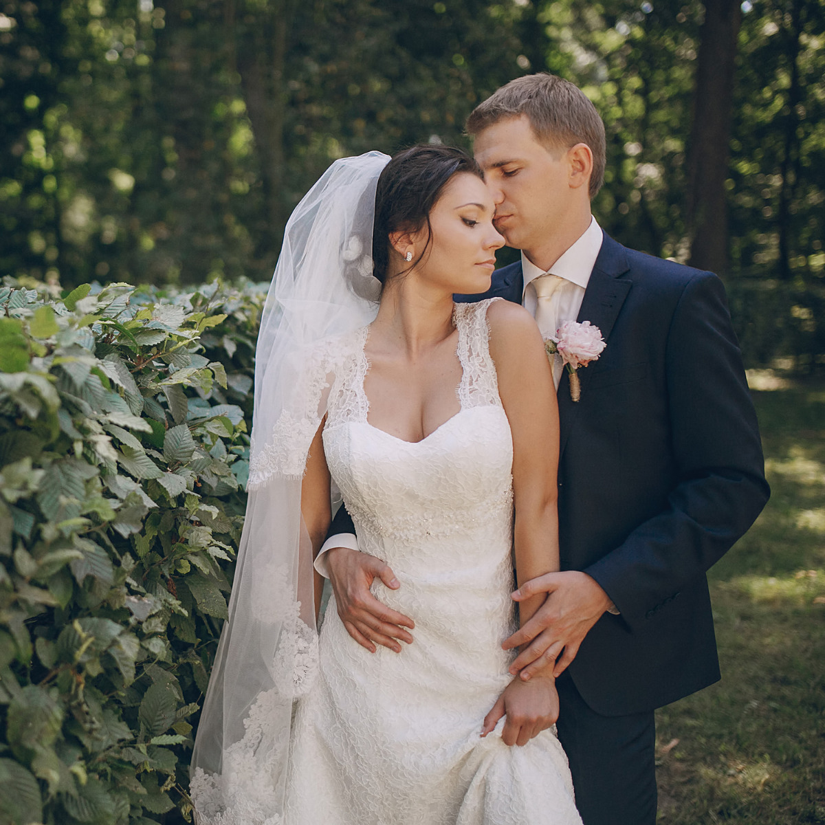Couple embracing in front of lush gardens
