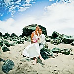 Gorgeous couple sitting on a rocky beach after their destination wedding