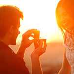 A man proposing to a woman at sunset, holding a ring, both bathed in golden light. This unique proposal idea creates a memorable moment.