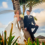 A couple leans against a palm tree after their destination wedding using a Caribbean Islands Wedding Package Under $5000