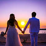 A couple holding hands on the beach at sunset during their wedding in Mexico.