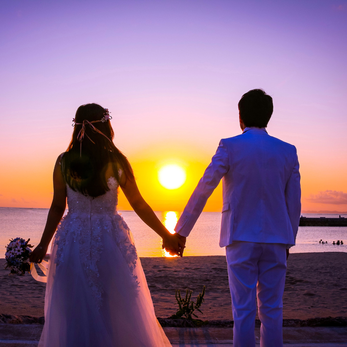 A couple holding hands on the beach at sunset during their wedding in Mexico.