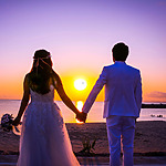 A bride and groom holding hands on the beach at sunset in Mexico.
