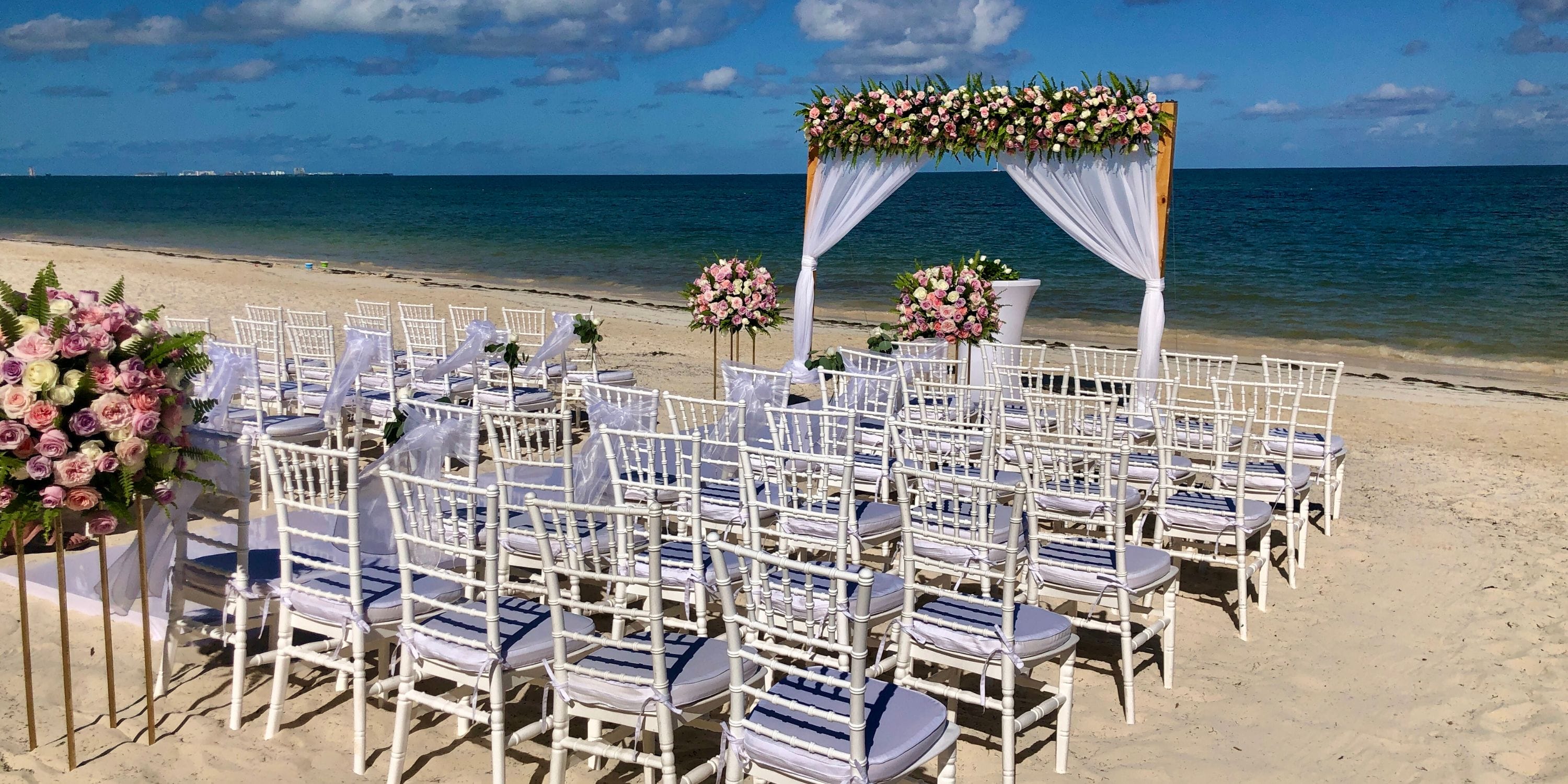 White chairs and a floral arch await a beautiful destination wedding at Royalton Splash Riviera Cancun.