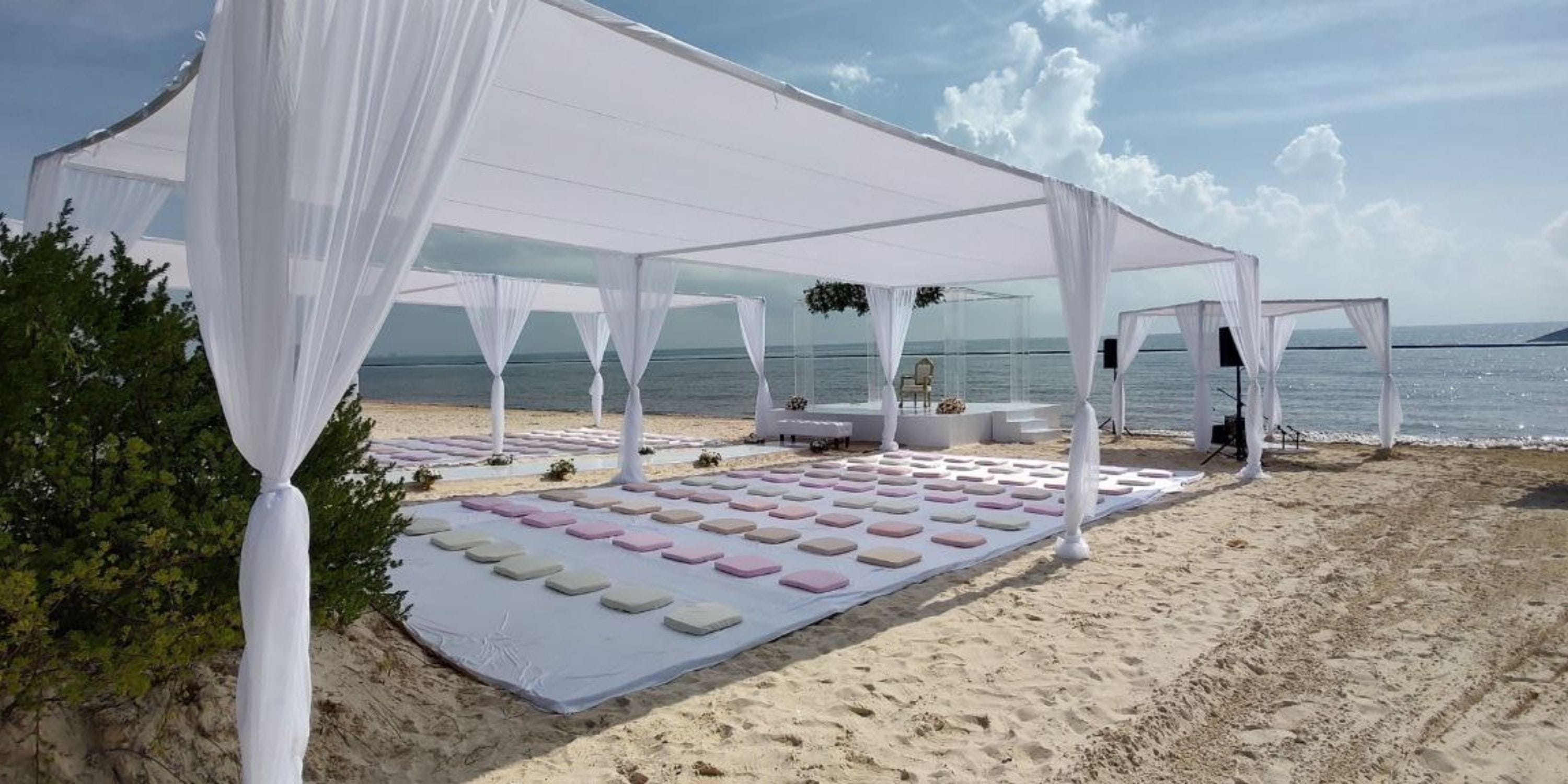 White canopies and cushions arranged for a destination wedding at Royalton Splash Riviera Cancun beach.
