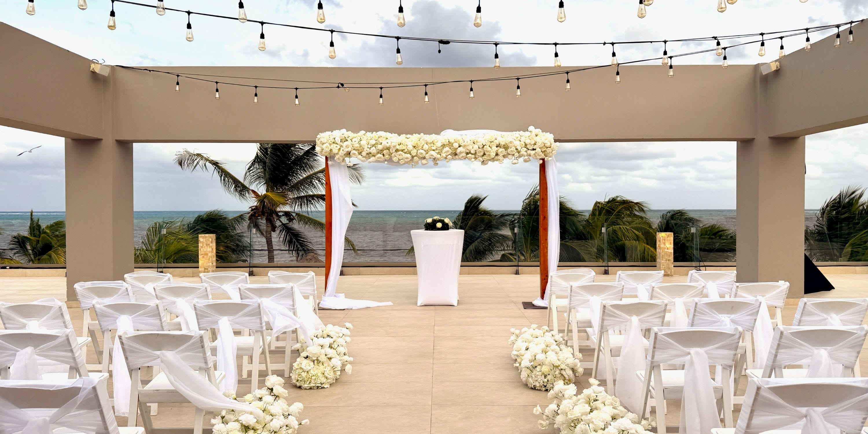 Destination wedding setup at Royalton Splash Riviera Cancun with white chairs, flowers, and ocean views.