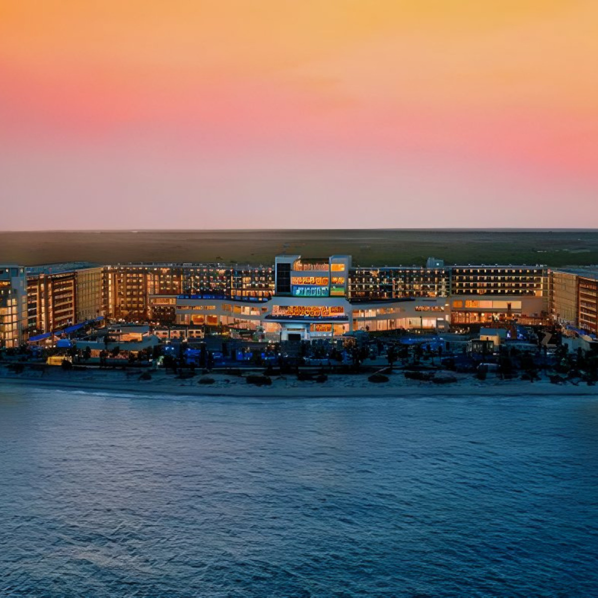 Aerial view of Royalton Splash Riviera Cancun illuminated at twilight, with a colorful sunset sky and calm ocean waters, perfect for destination weddings.