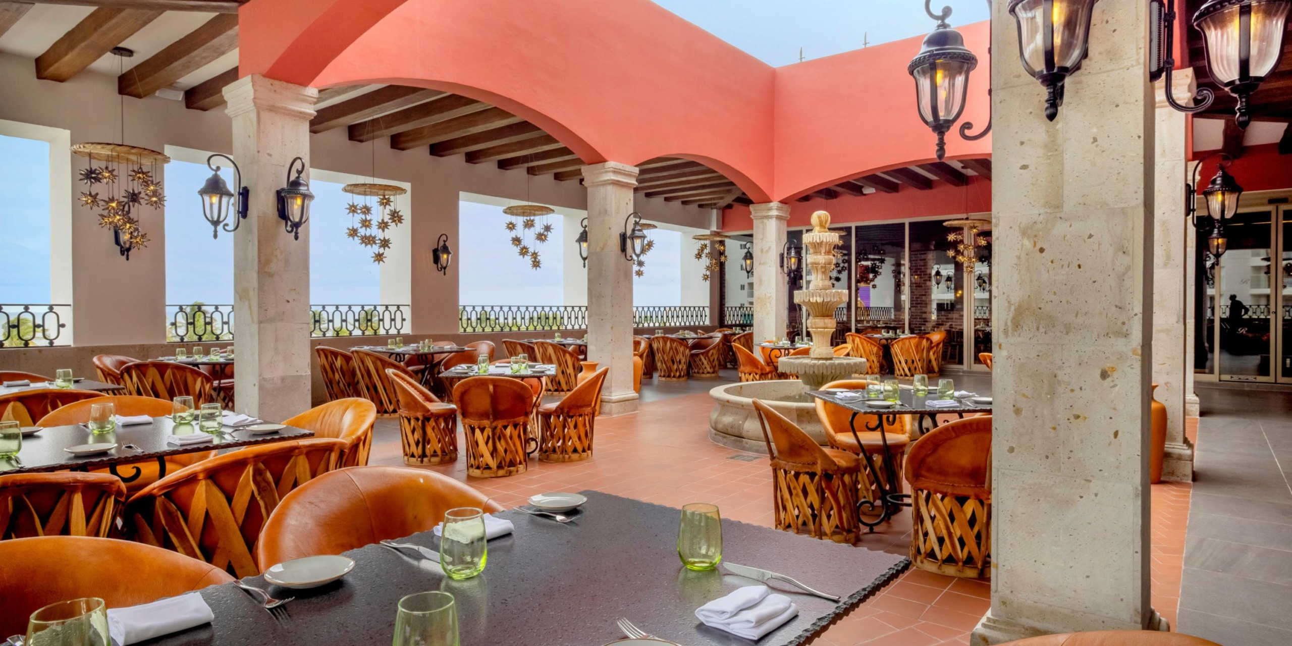 Royalton Splash Riviera Cancun offers an enchanting setting for a destination wedding, featuring wooden tables, brown leather chairs, and elegant hanging lanterns.
