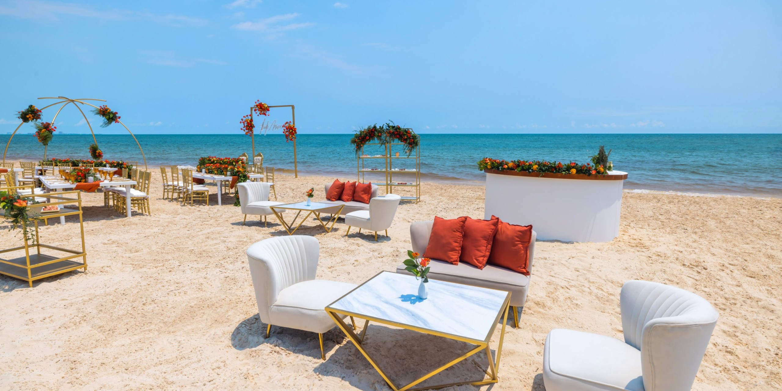 Royalton Splash Riviera Cancun offers a picturesque beachside setting perfect for a destination wedding, with its sunny seating featuring elegant white furniture accented by vibrant orange tones.