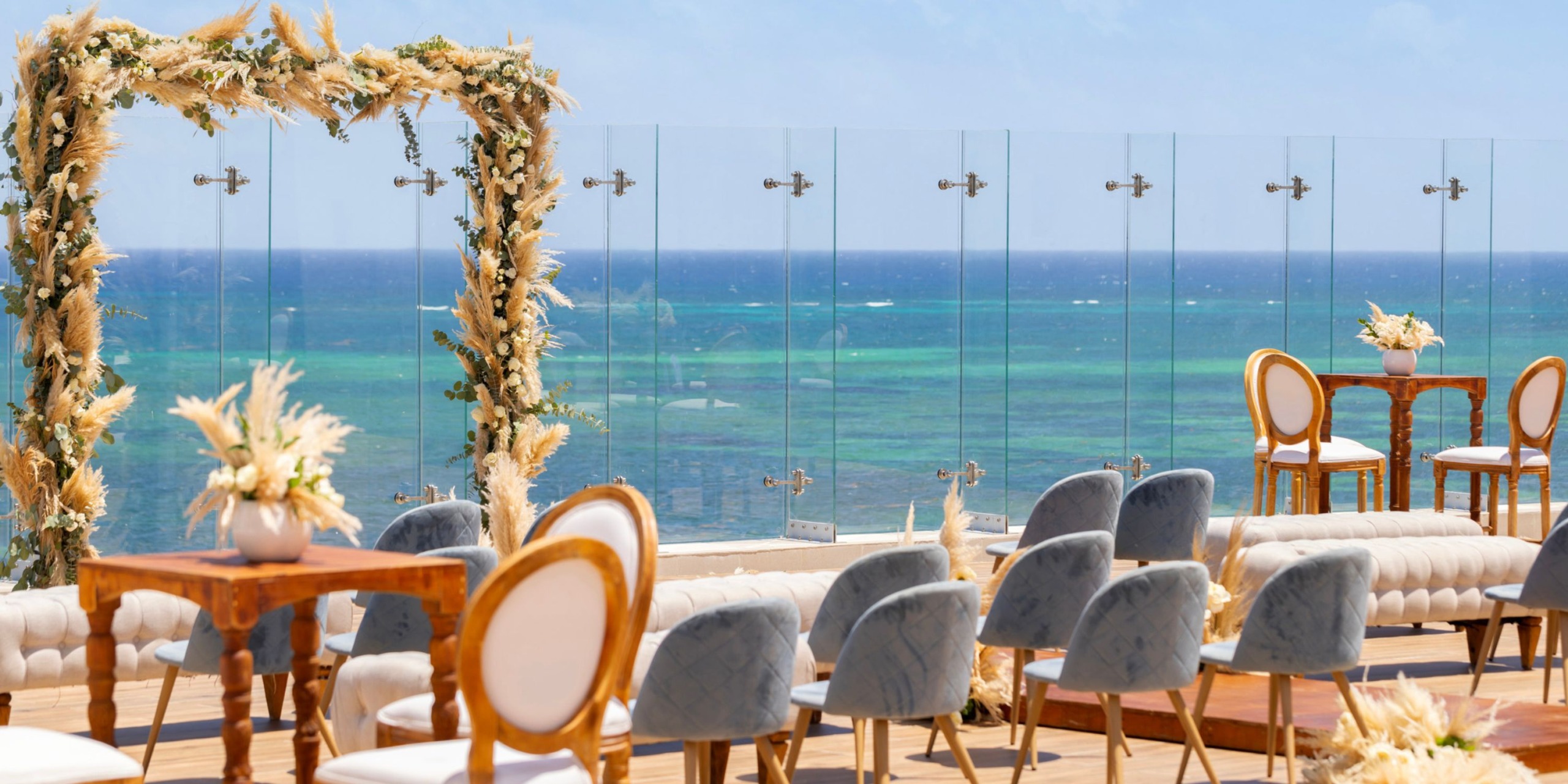 A beautiful destination wedding arrangement at Royalton Splash Riviera Cancun, featuring an oceanfront setting with chairs and a floral arch.
